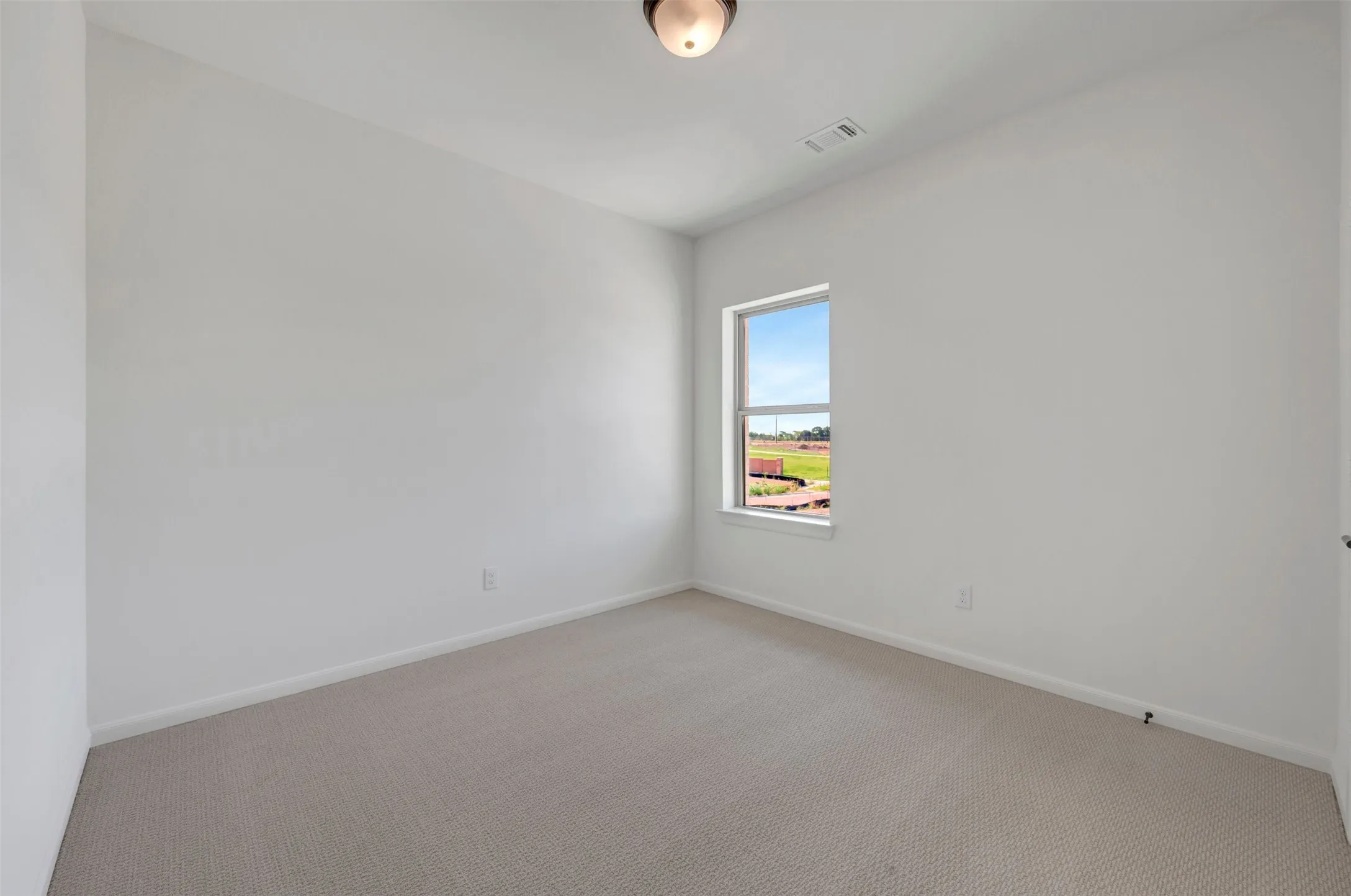 Room featuring light-toned carpeting, white walls, and a single window with white trim