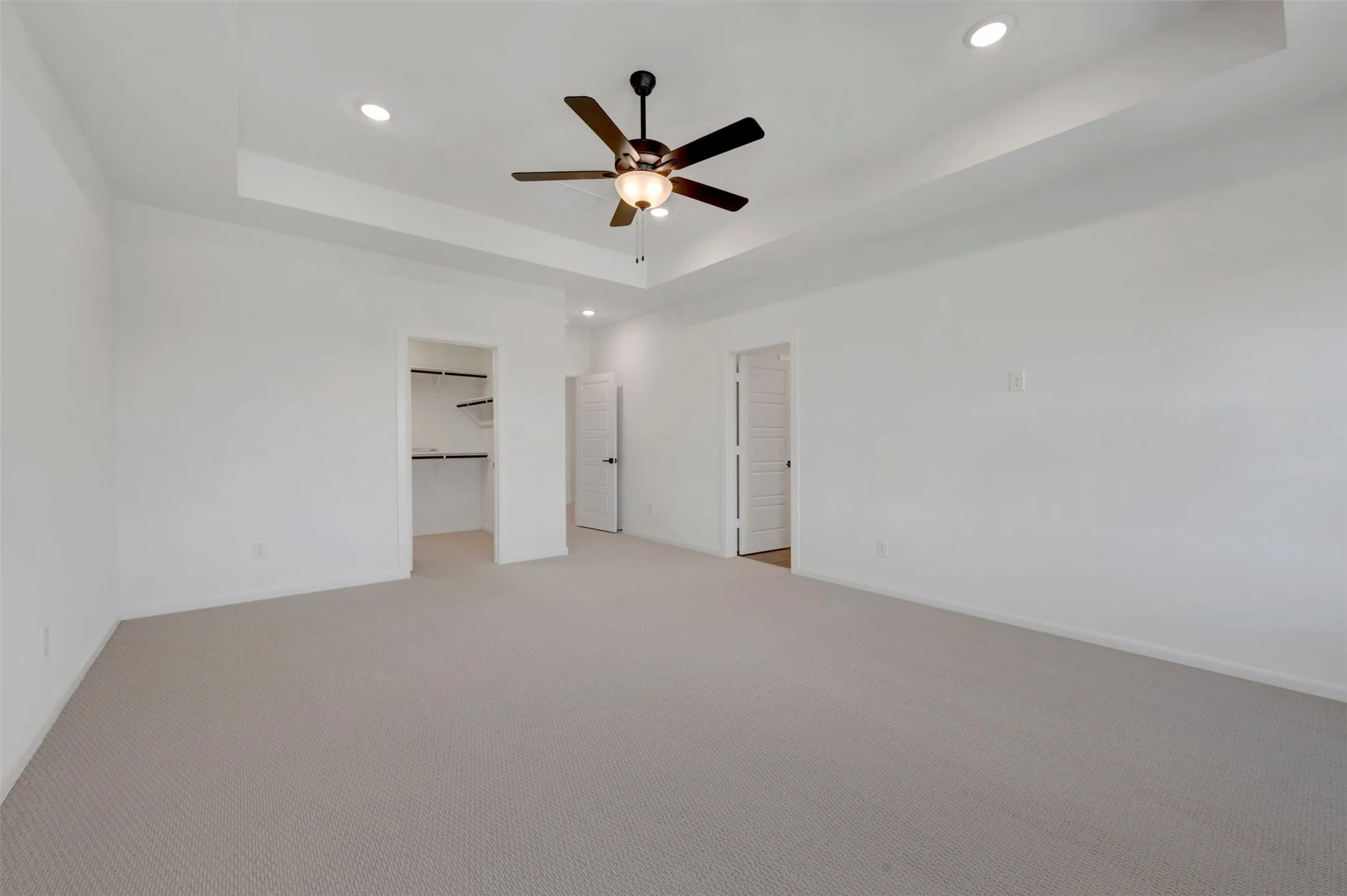 Spacious interior with neutral carpeting and a tray ceiling