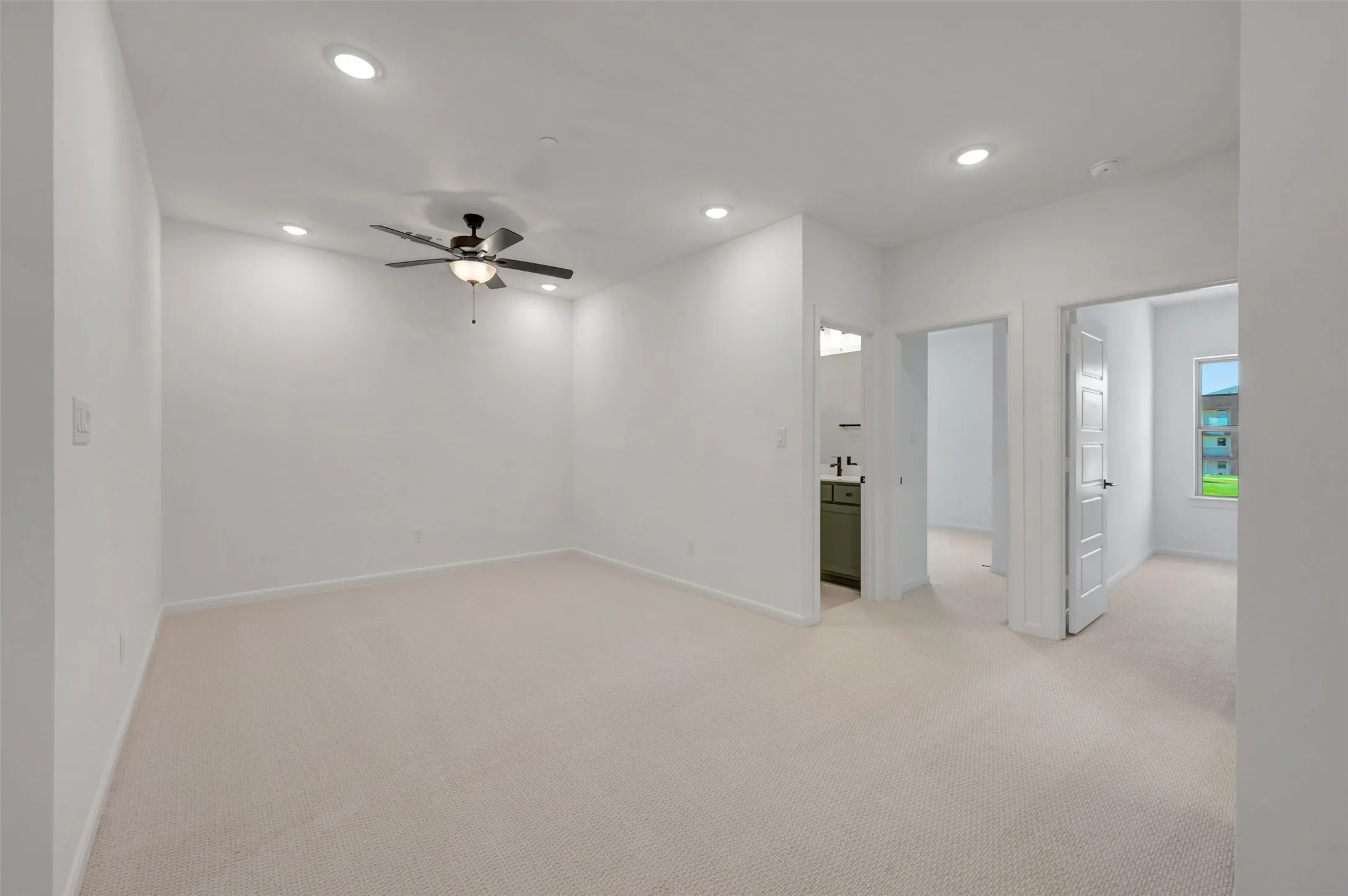 Spacious room featuring neutral carpet flooring, recessed lighting, and a ceiling fan