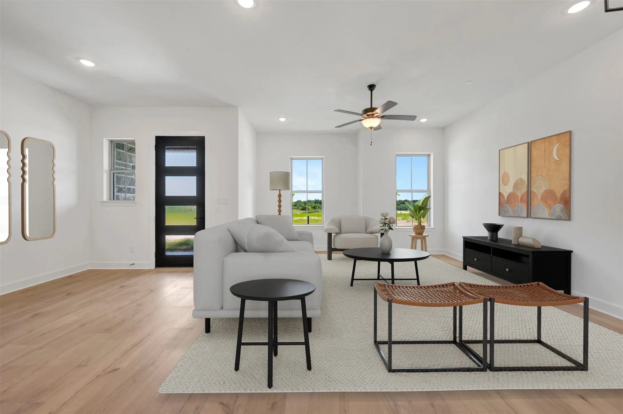 Spacious living area featuring light wood-finish flooring, recessed lighting, and a contemporary ceiling fan