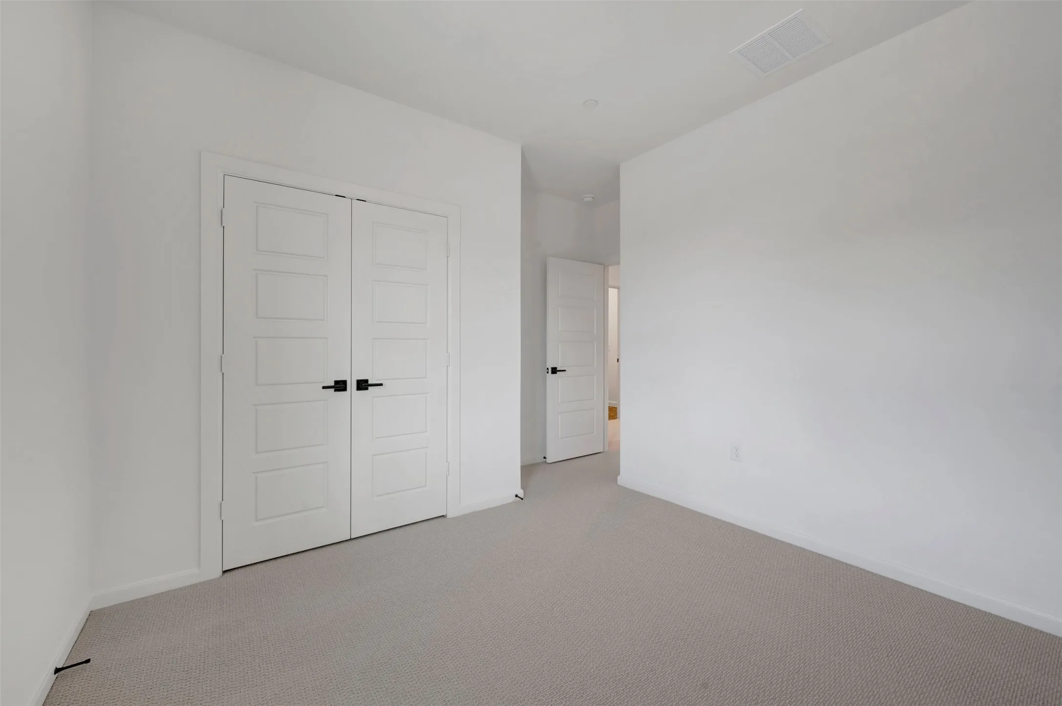 Neutral tone carpeting extends throughout this room, featuring white walls and white trim