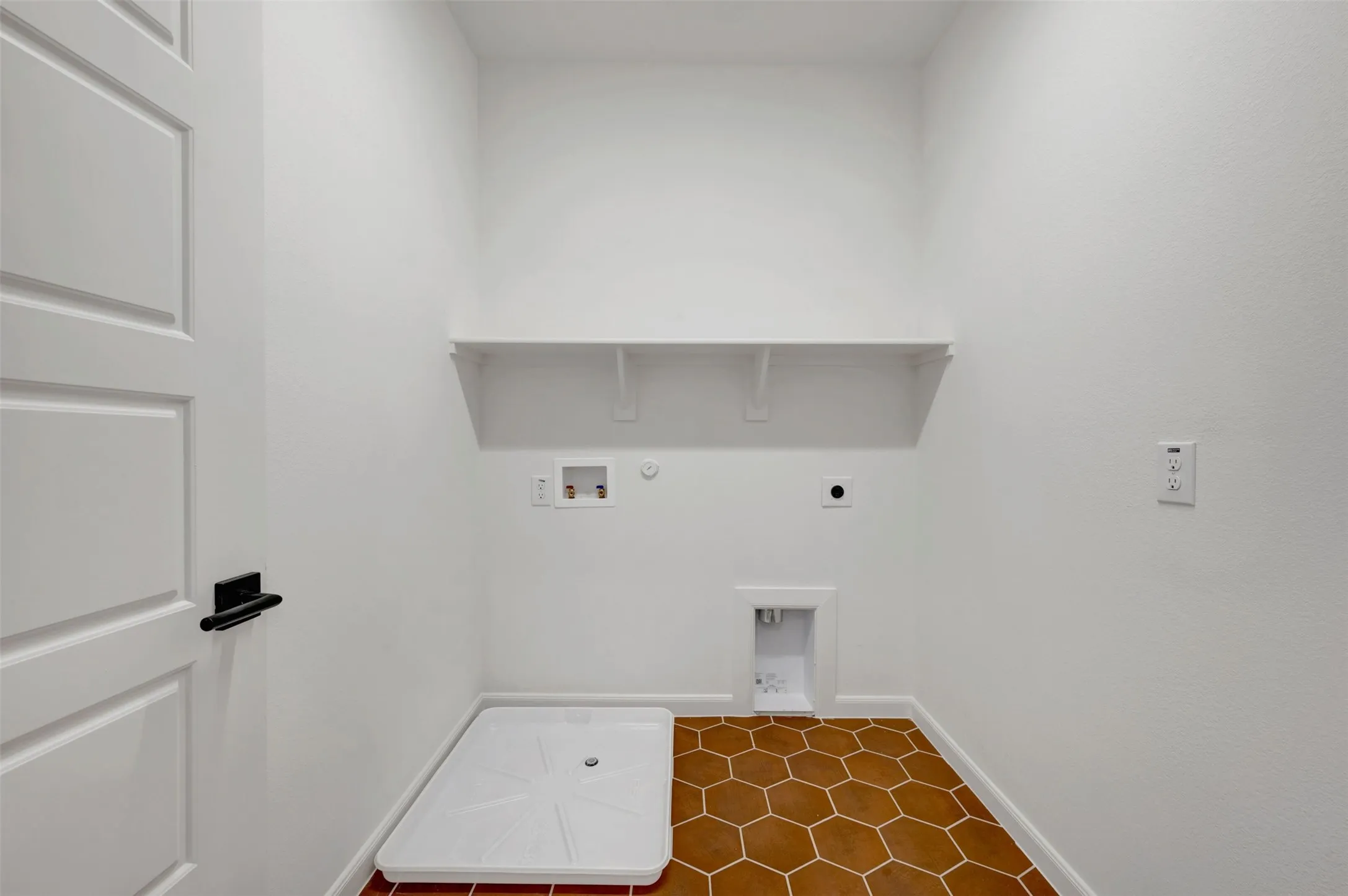 Laundry area featuring hexagon floor tiling, a white built-in shelf, and a utility tray