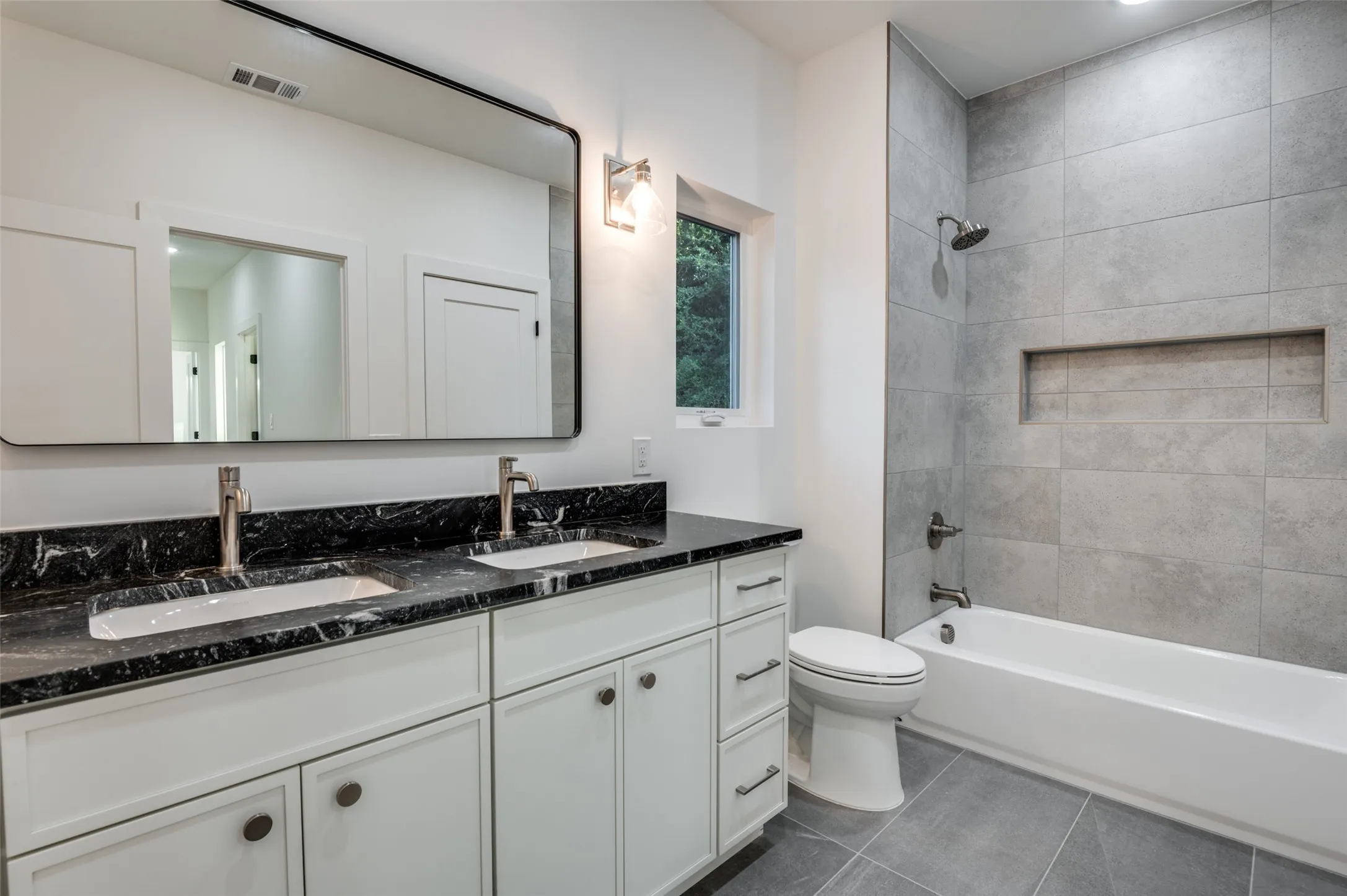 Bathroom featuring double vanity, tile patterned flooring, and shower / tub combination