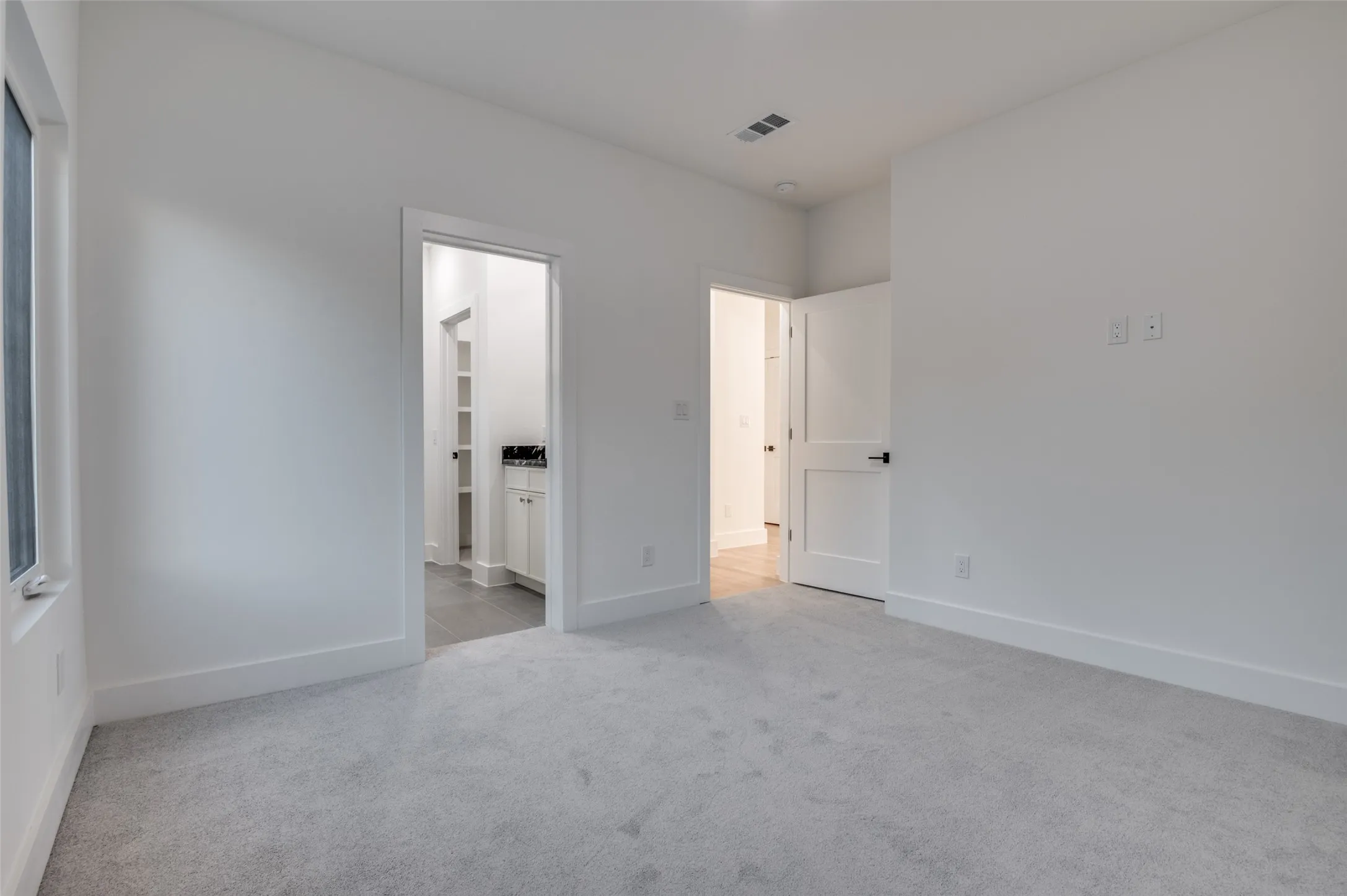Unfurnished bedroom featuring light carpet and ensuite bath