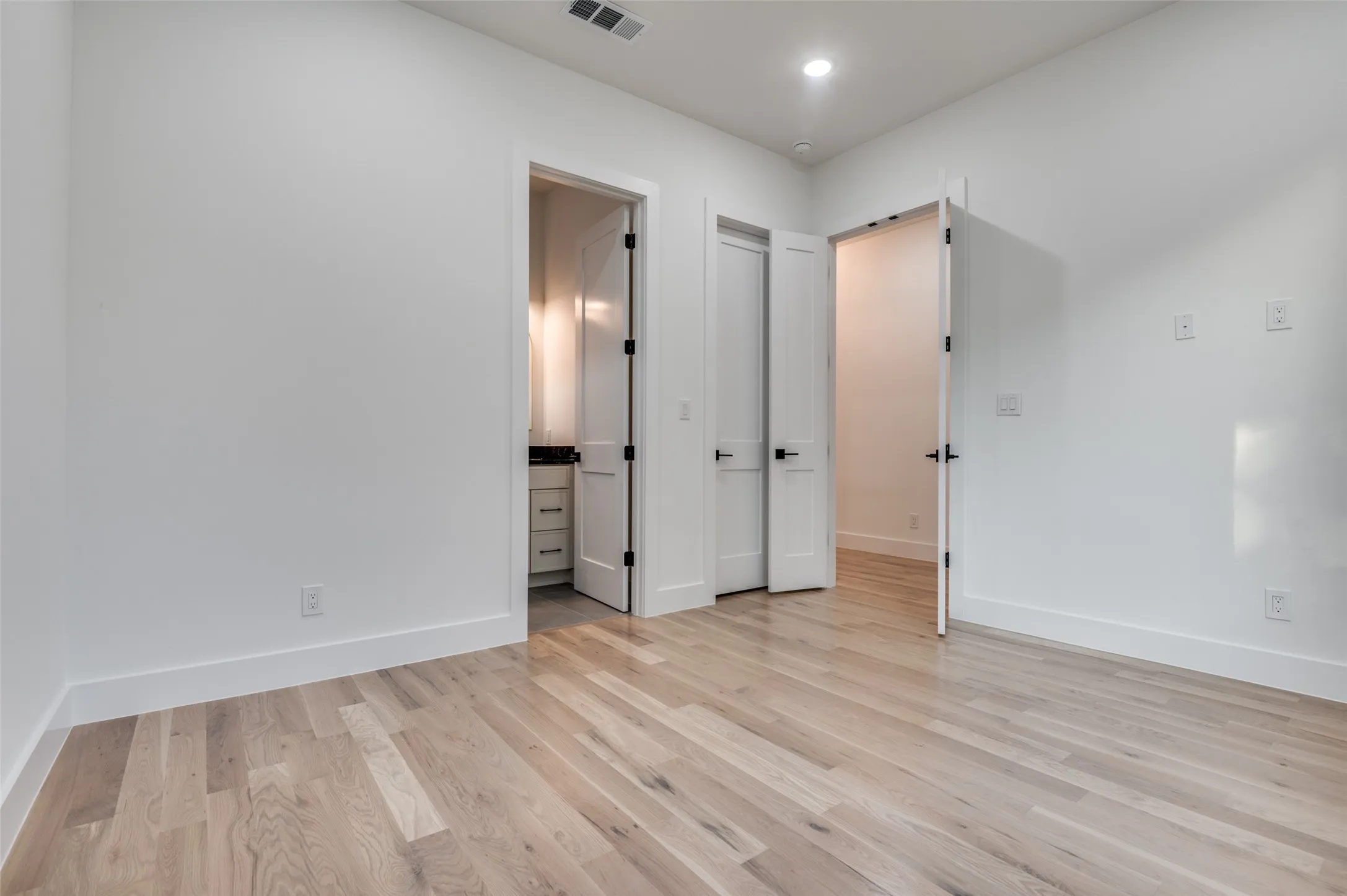 Unfurnished bedroom featuring light wood-style floors, recessed lighting, and ensuite bath