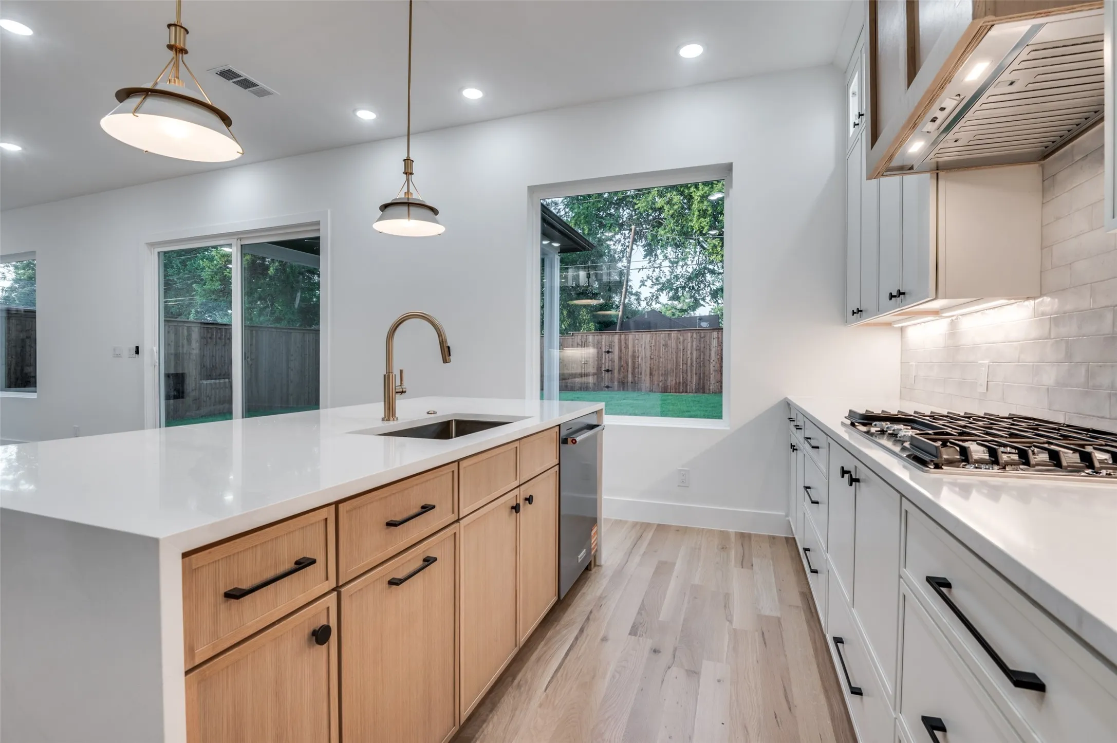 Kitchen featuring recessed lighting, premium range hood, light wood-type flooring, light countertops, and light brown cabinets