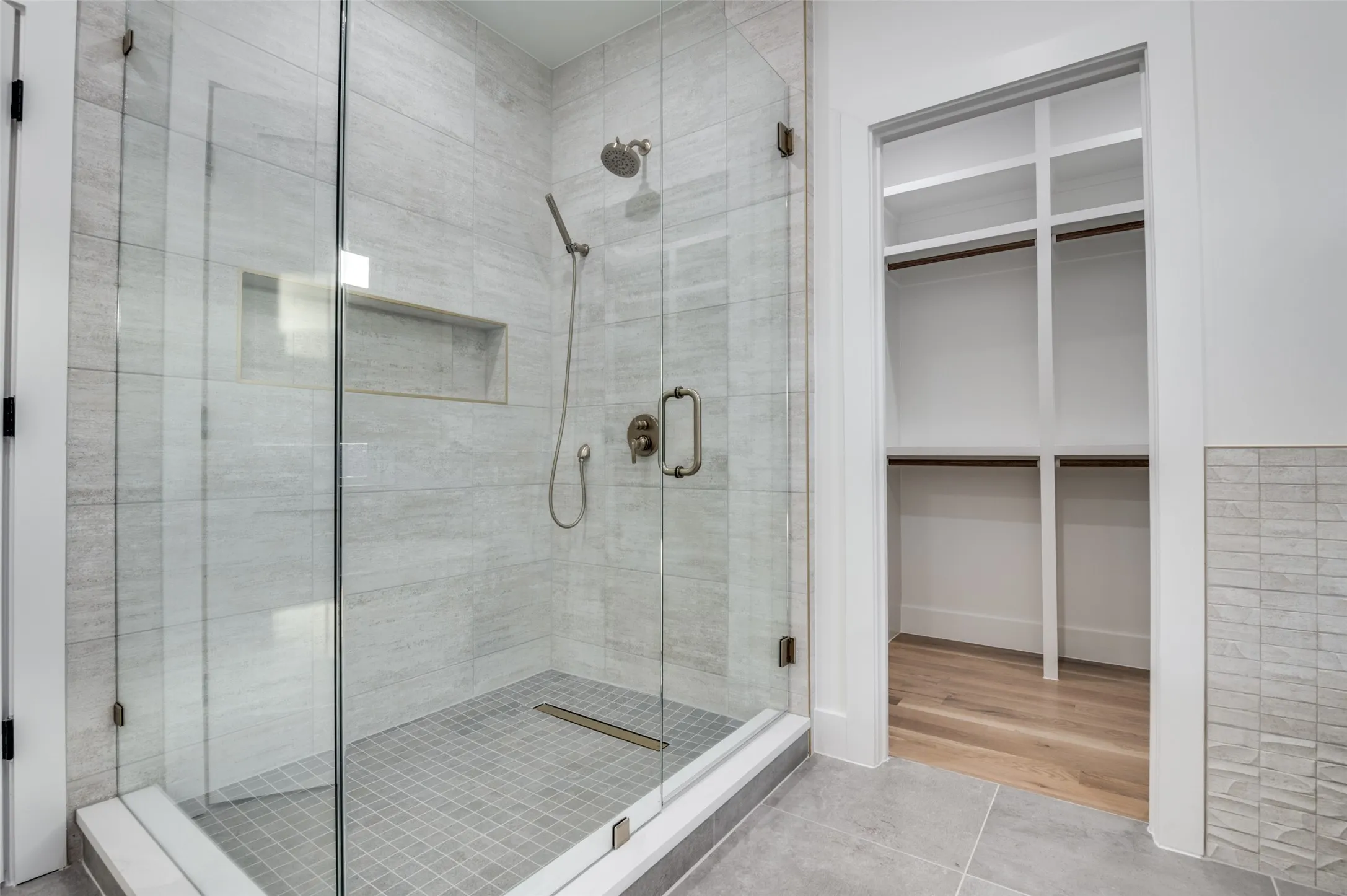 Bathroom with a shower stall, a spacious closet, and tile patterned floors