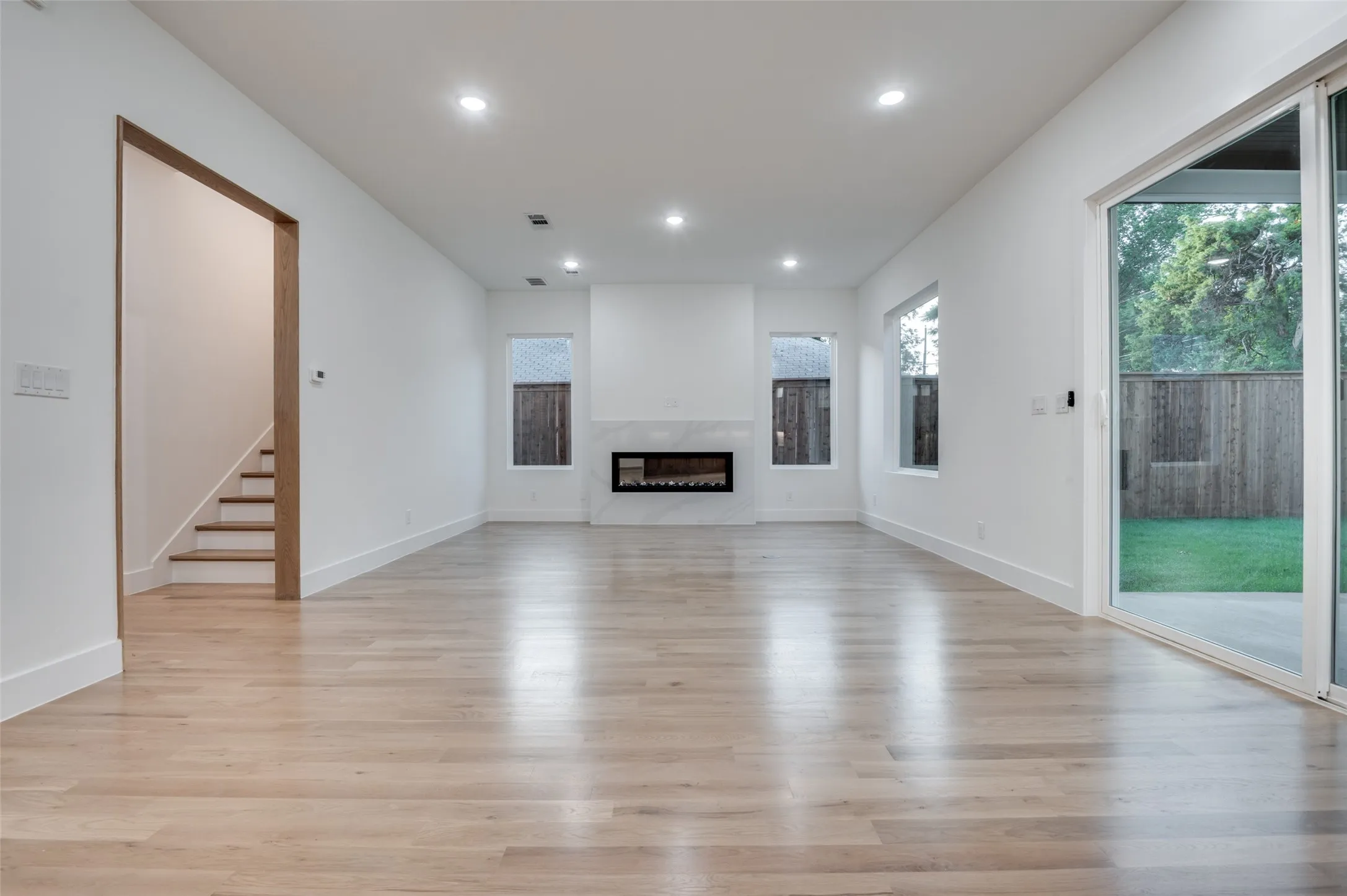 Unfurnished living room featuring light wood-type flooring, a fireplace, recessed lighting, and stairs