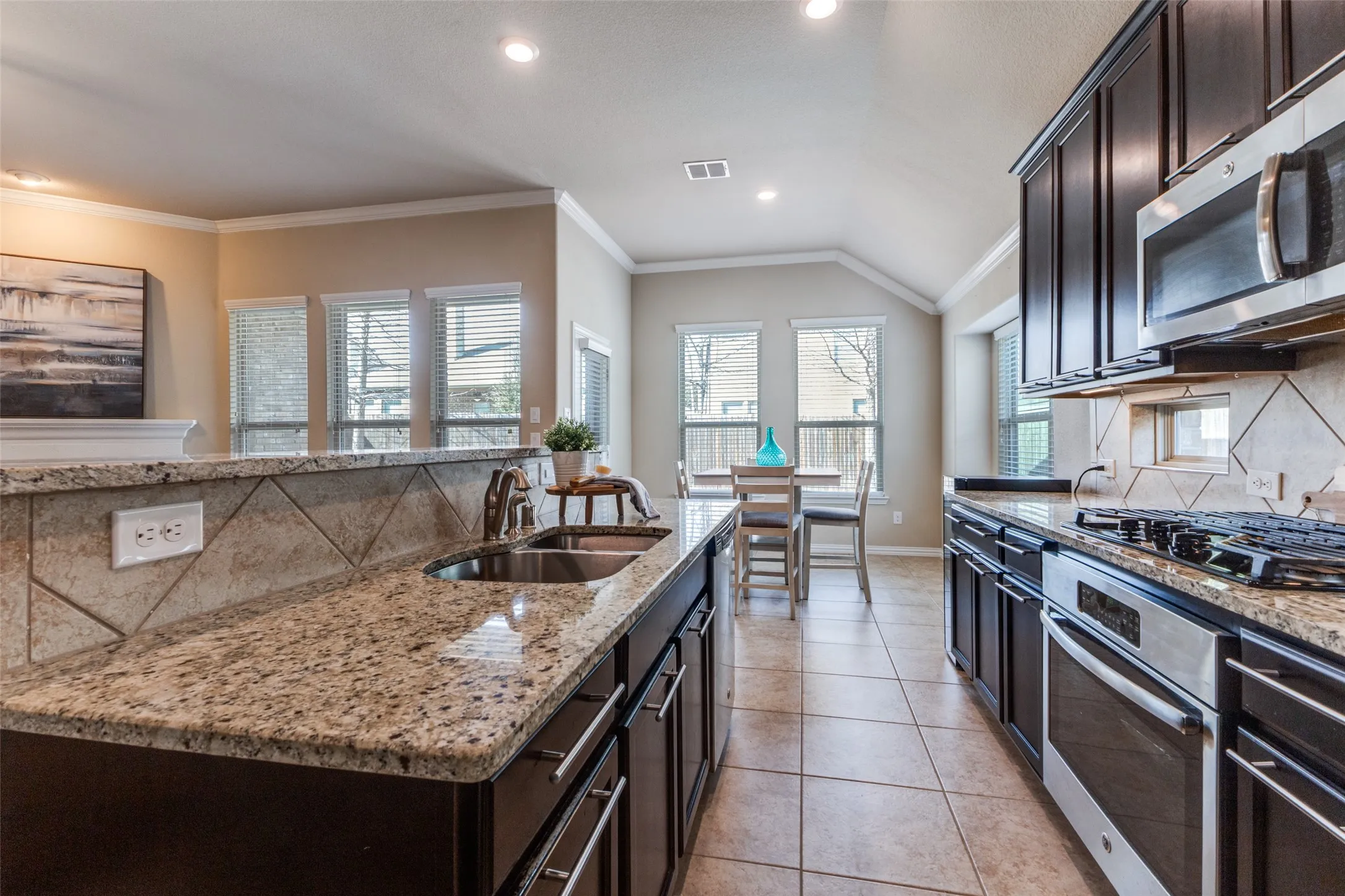 The kitchen features a gas cooktop, island, built in microwave and granite countertops.