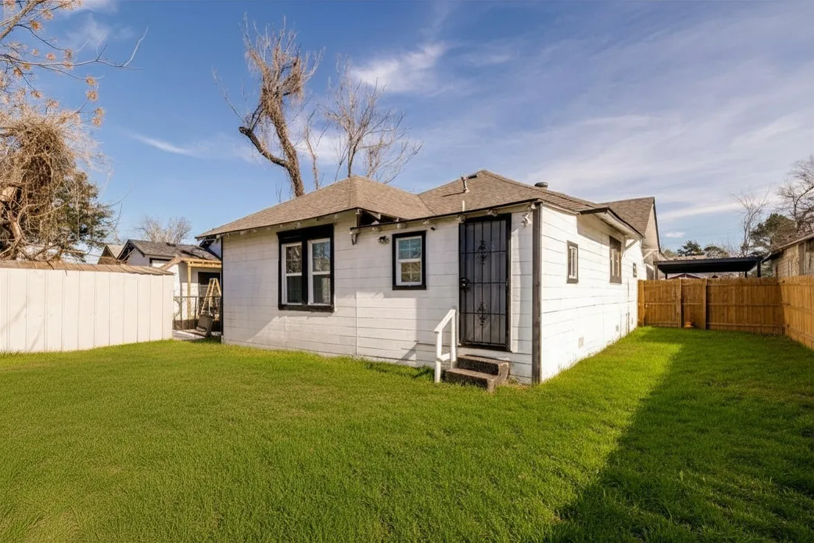 Rear view of house featuring a fenced backyard, entry steps, and roof with shingles