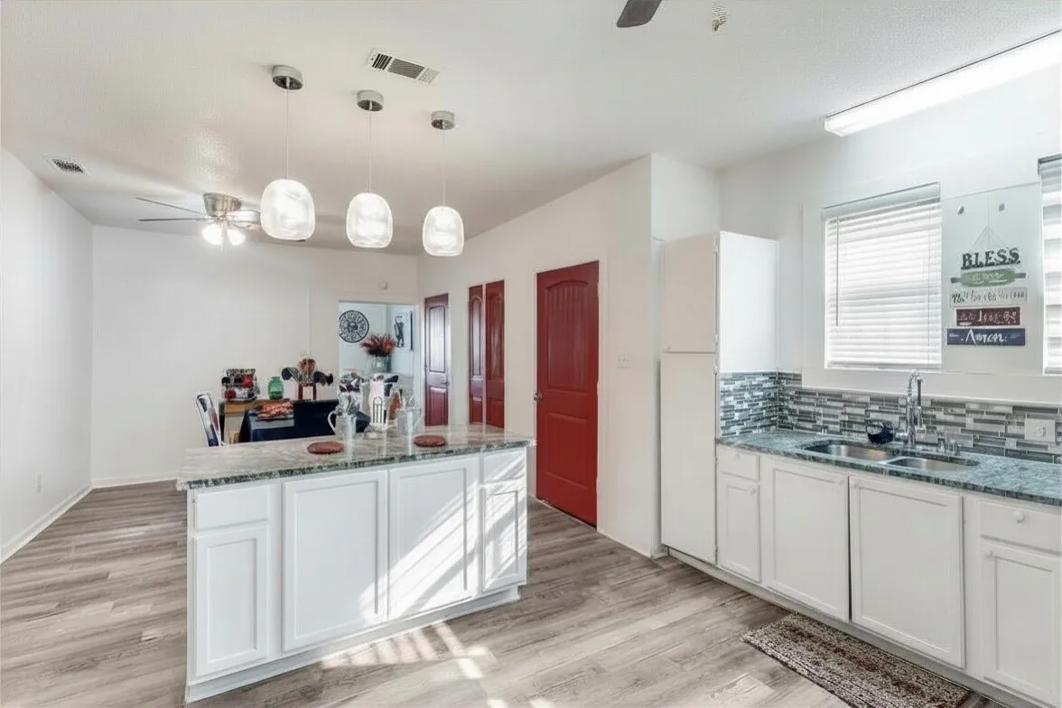Kitchen featuring a ceiling fan, white cabinets, and light stone counters
