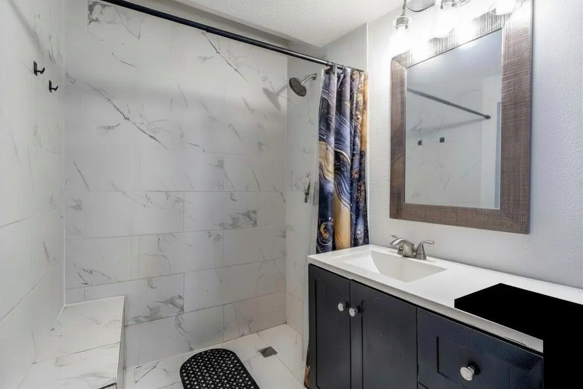 Full bath featuring vanity and a marble finish shower