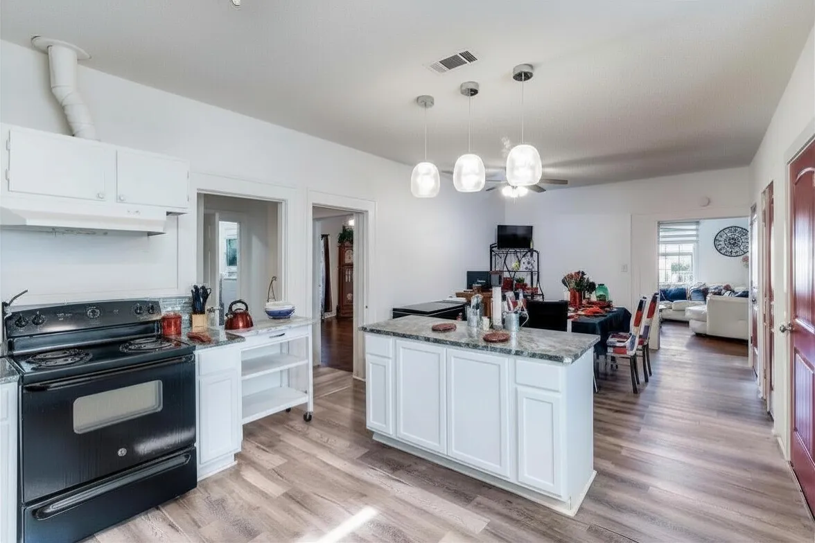 Kitchen featuring black / electric stove, white cabinetry, light stone countertops, and open floor plan