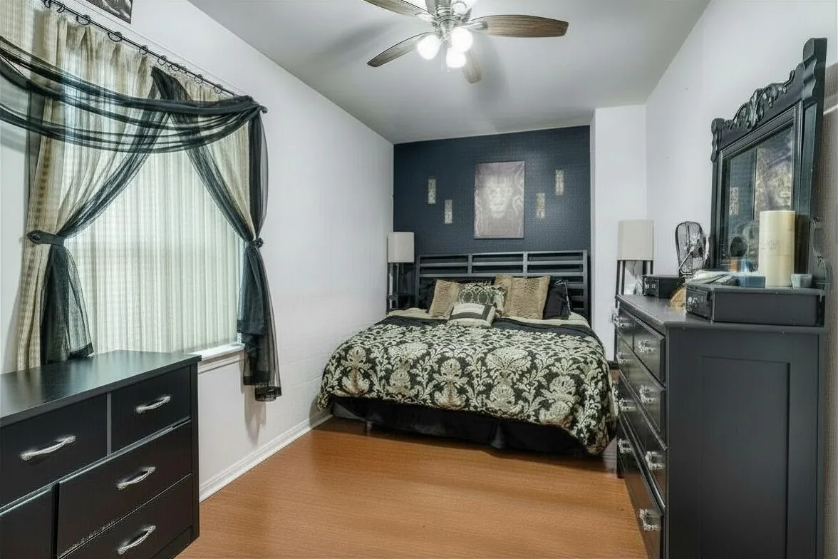 Bedroom with a ceiling fan and an accent wall