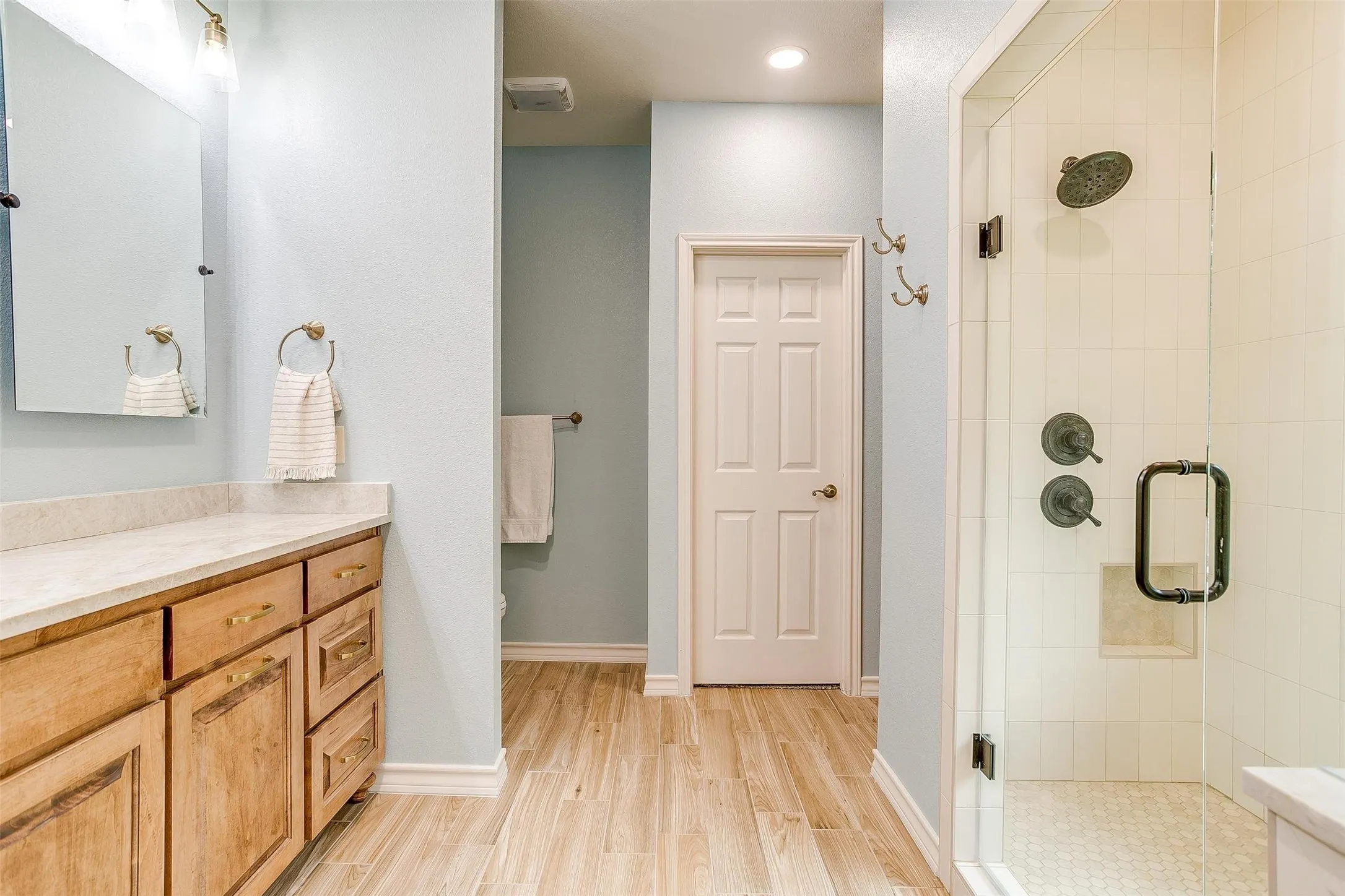 Bathroom featuring vanity, a shower stall, light wood-style floors, and recessed lighting