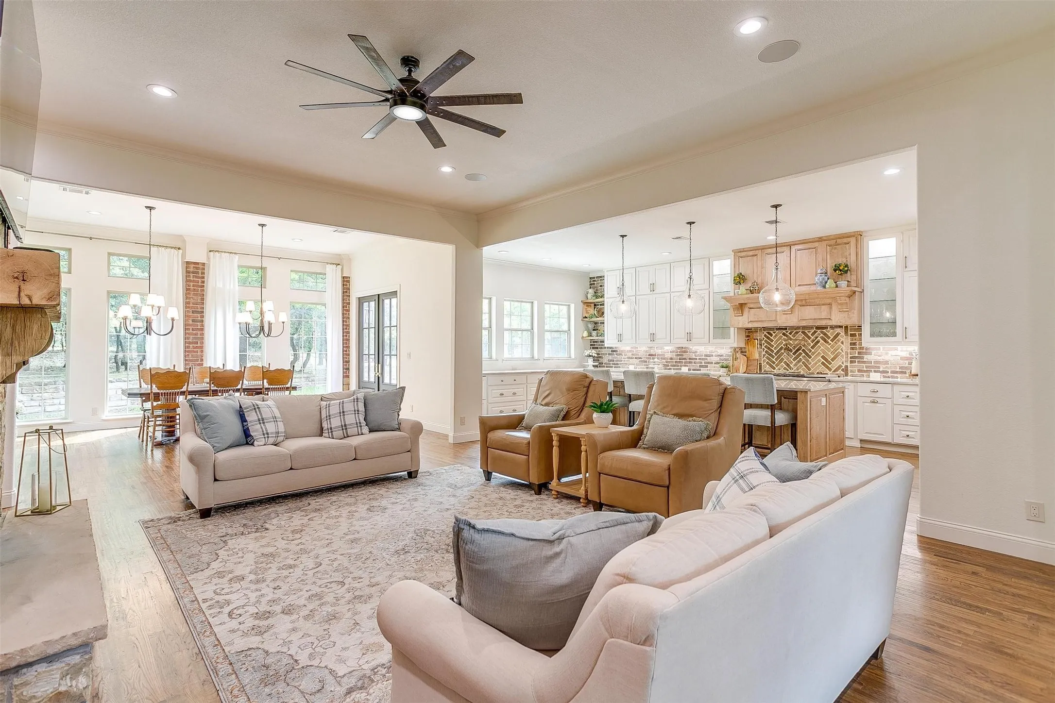 Living room featuring ceiling fan, hanging lights, light wood-style floors, and crown molding