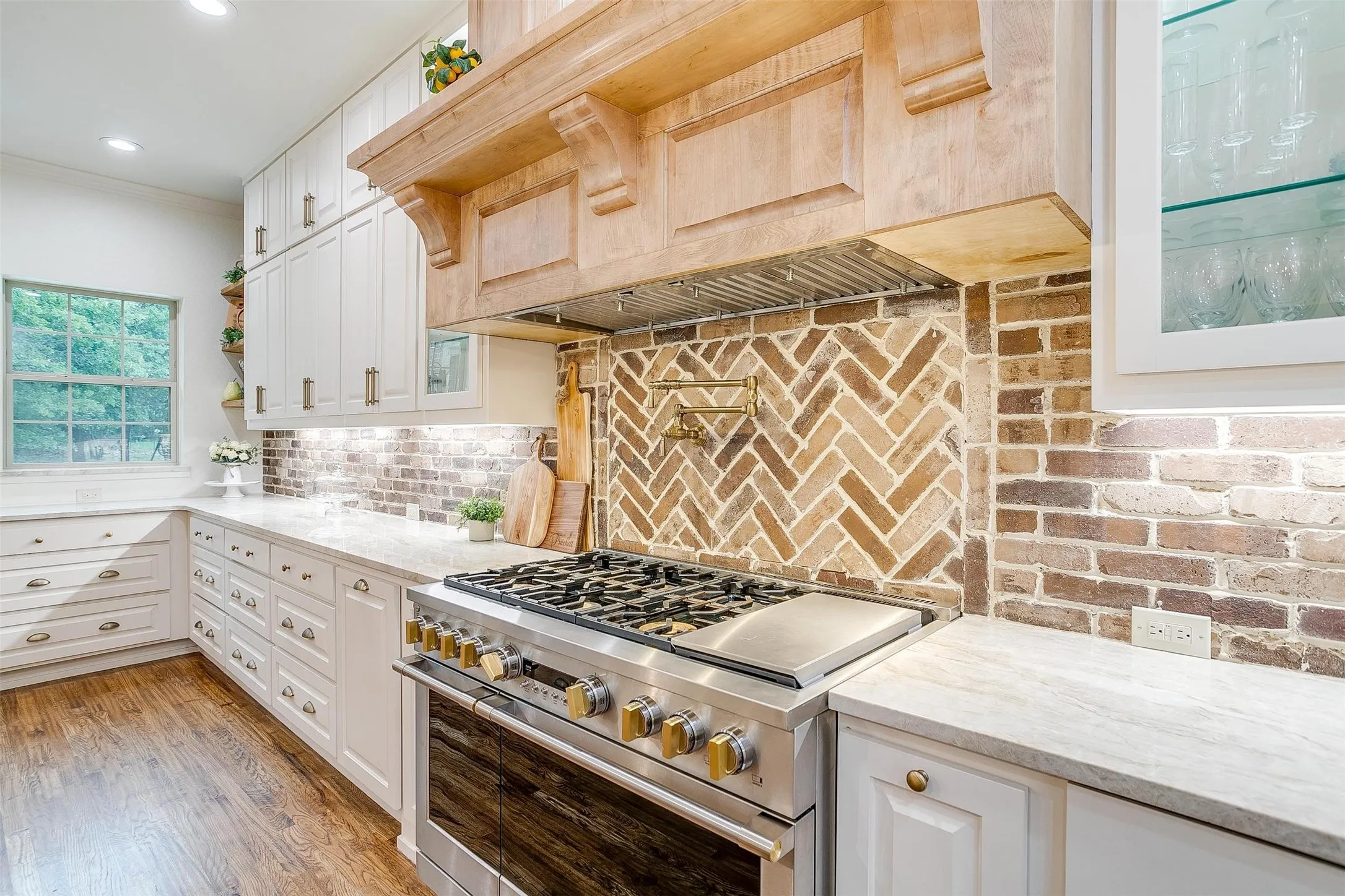 Kitchen with high end stove, light stone counters, glass insert cabinets, white cabinetry, and ornamental molding
