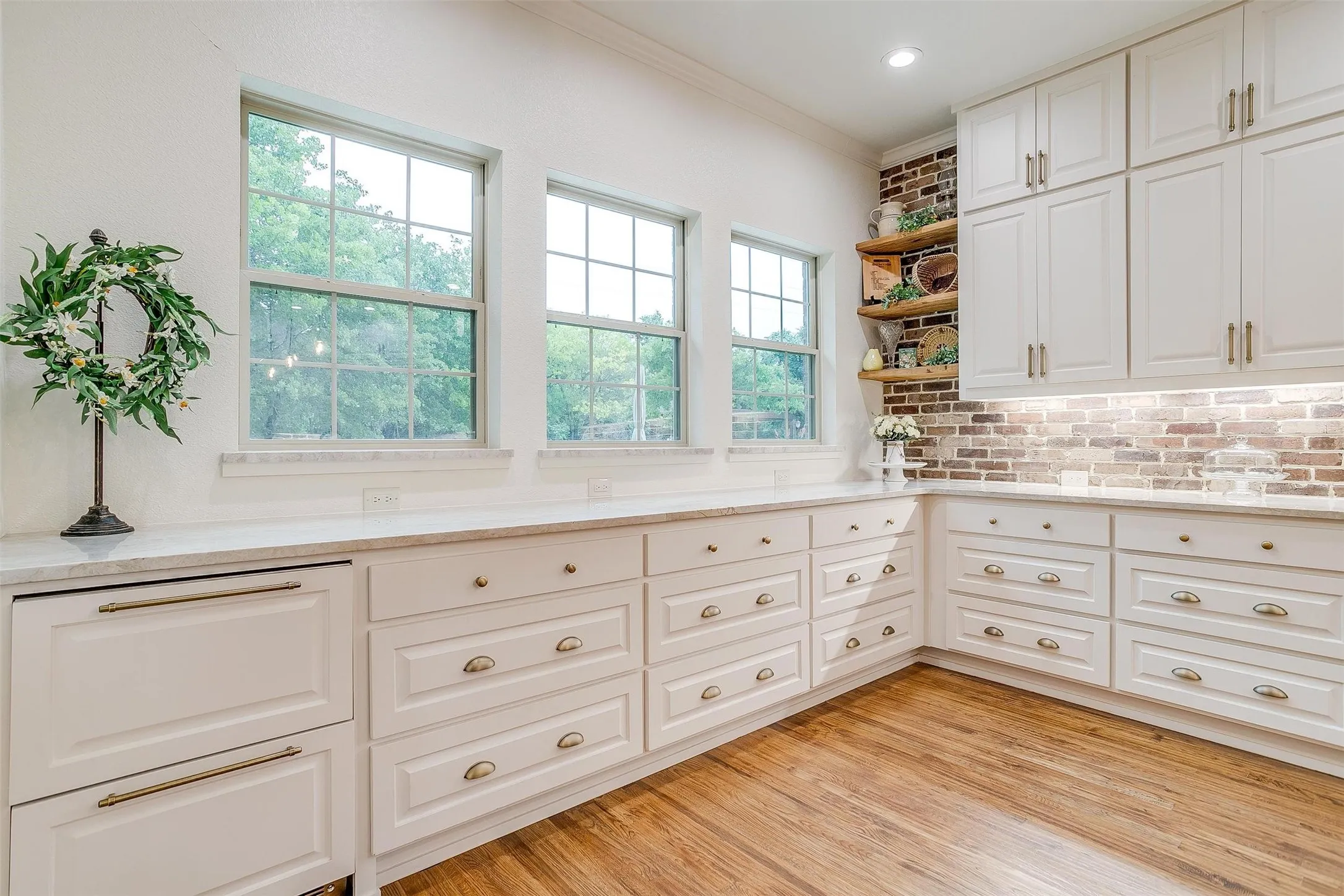 Kitchen featuring white cabinetry, light stone countertops, ornamental molding, light wood-type flooring, and open shelves