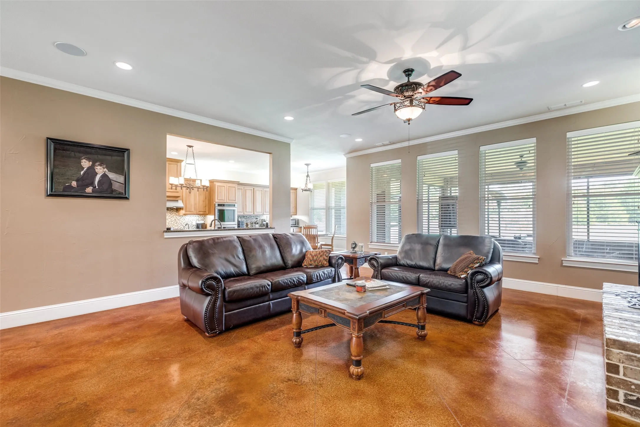 Living room with crown molding, finished concrete flooring, recessed lighting, and ceiling fan