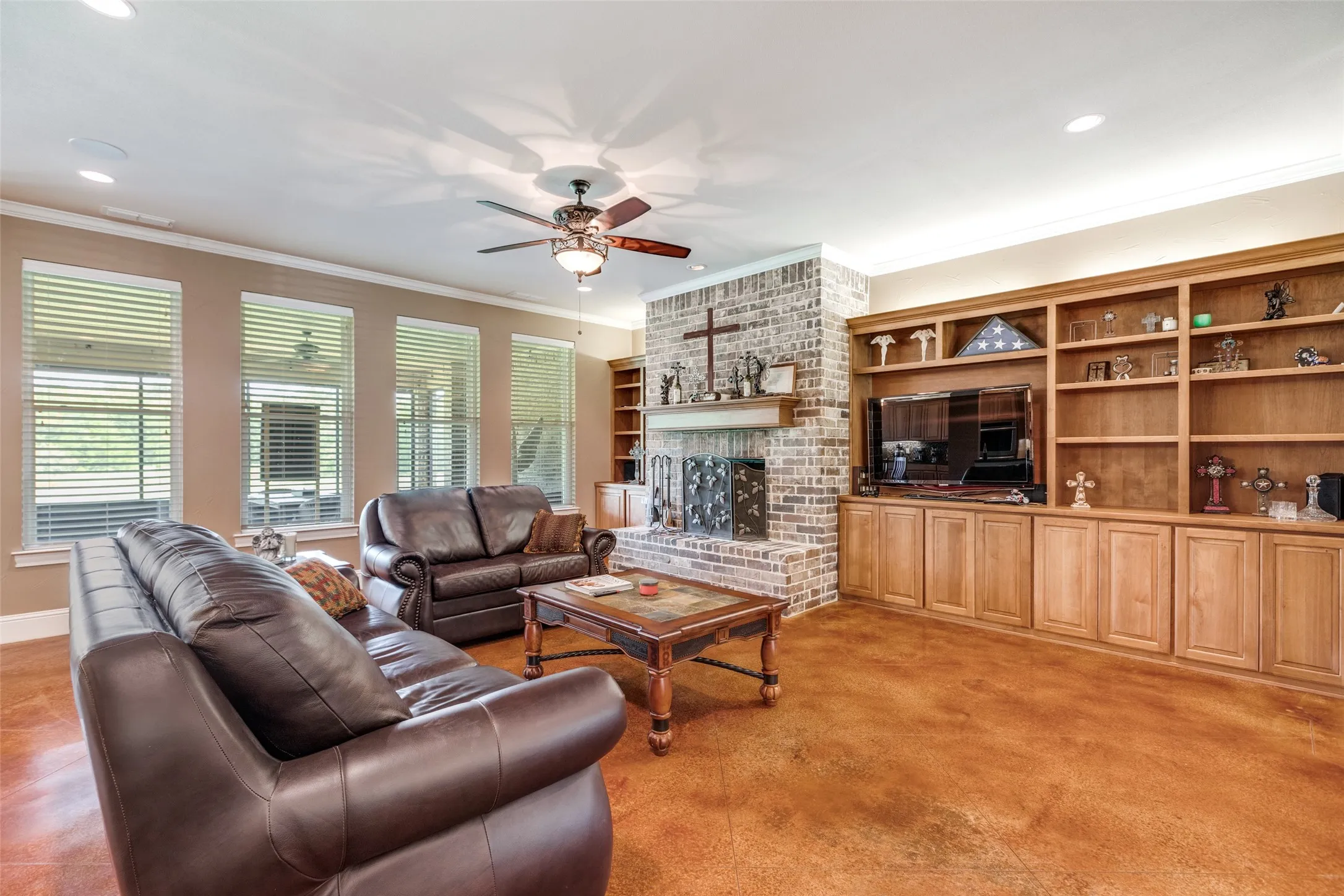 Living room featuring a brick fireplace, ornamental molding, a ceiling fan, recessed lighting, and built in features