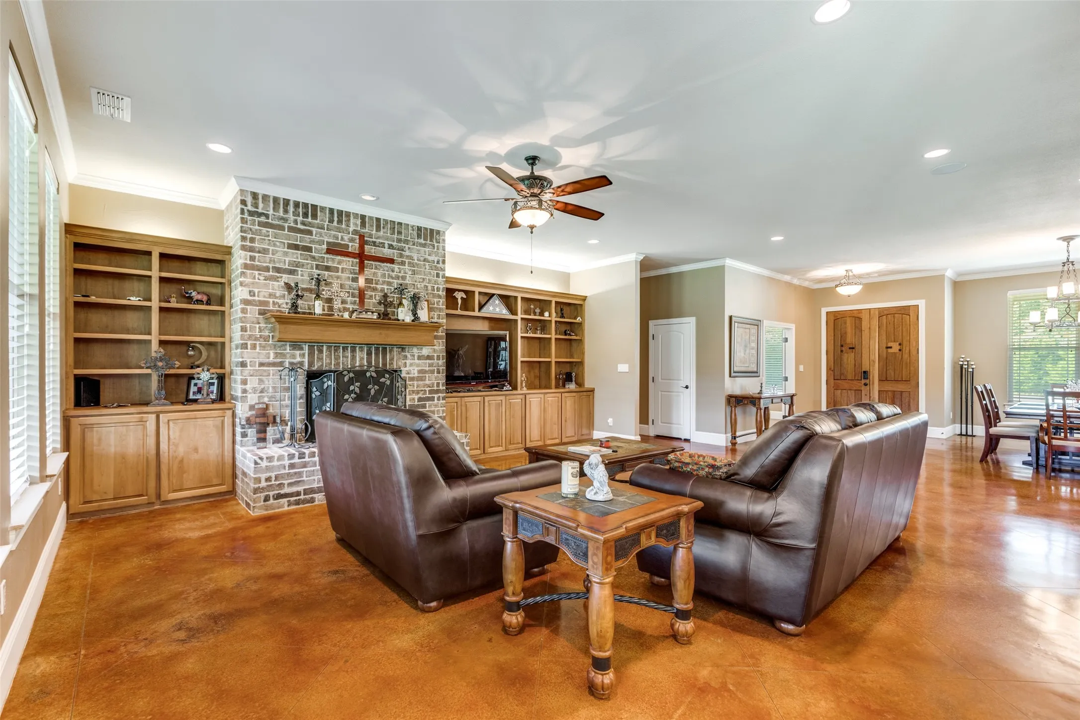 Living area featuring finished concrete flooring, a fireplace, recessed lighting, crown molding, and ceiling fan
