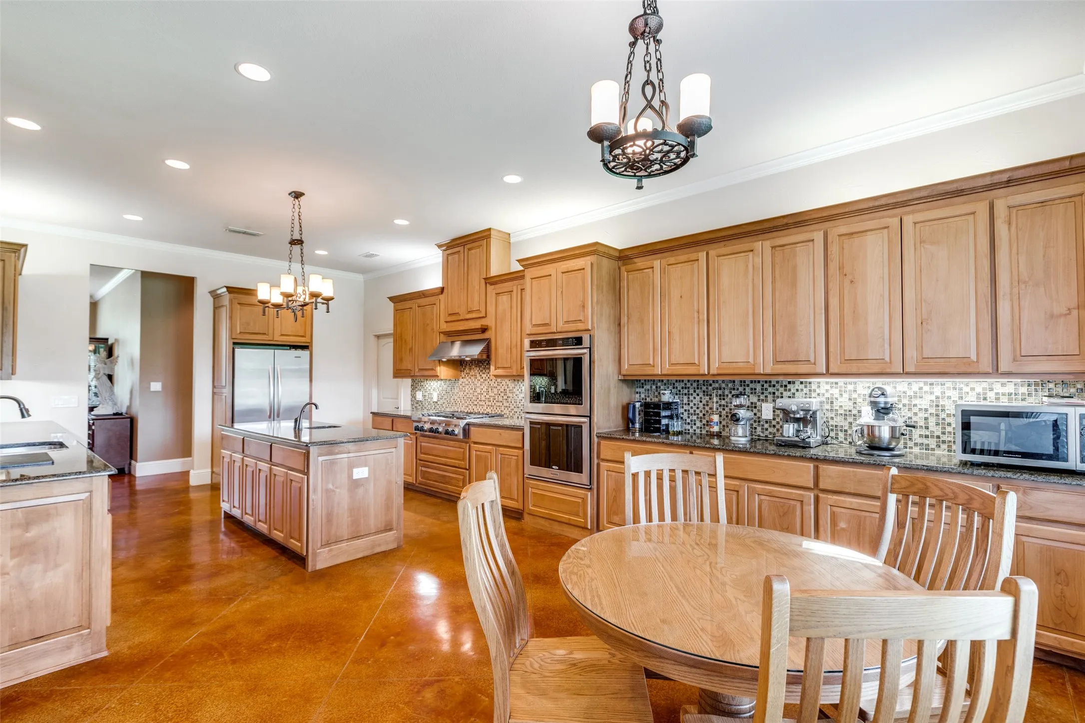 Kitchen featuring a chandelier, pendant lighting, crown molding, backsplash, and appliances with stainless steel finishes