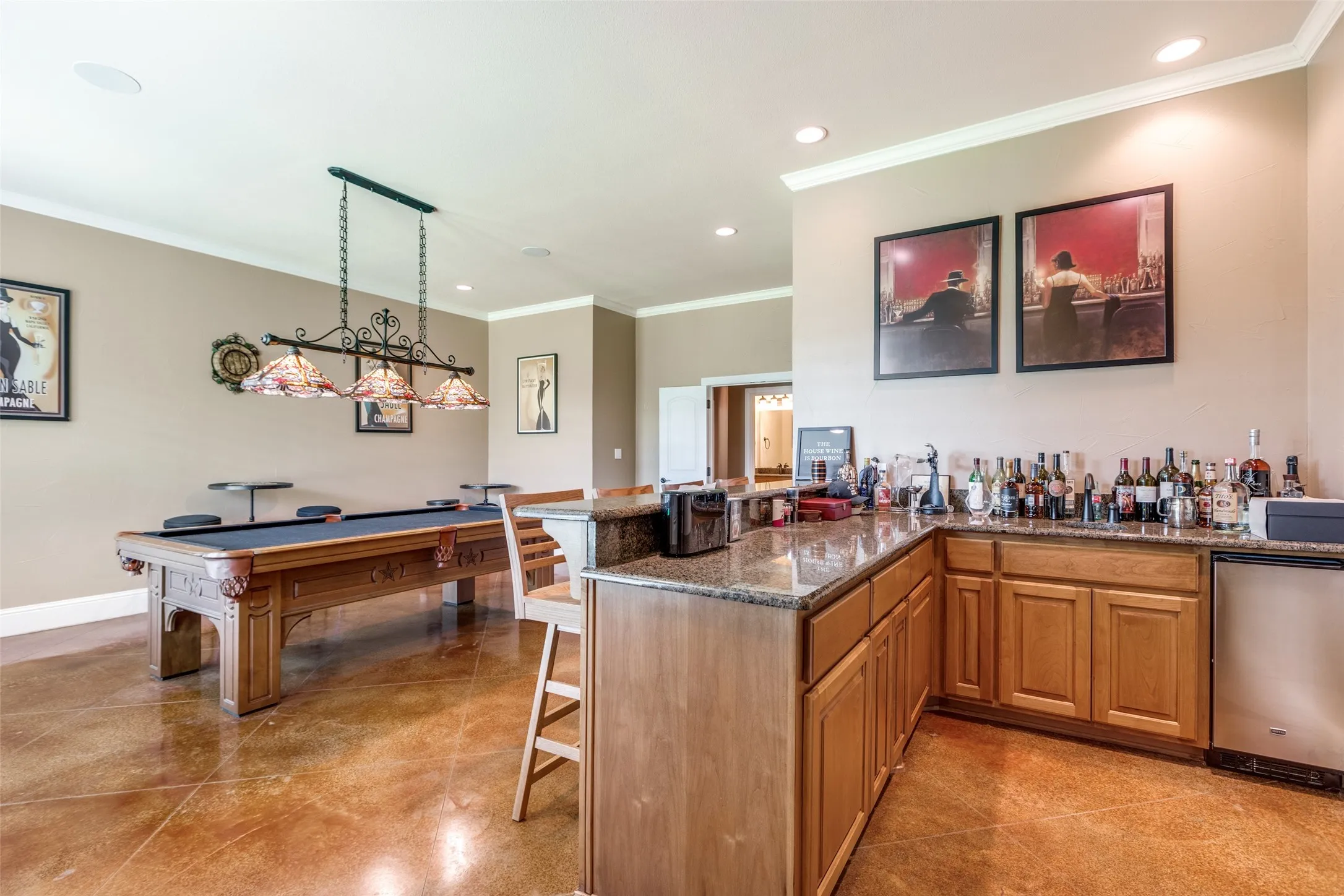 Indoor wet bar featuring recessed lighting, ornamental molding, dark stone counters, pendant lighting, and brown cabinetry