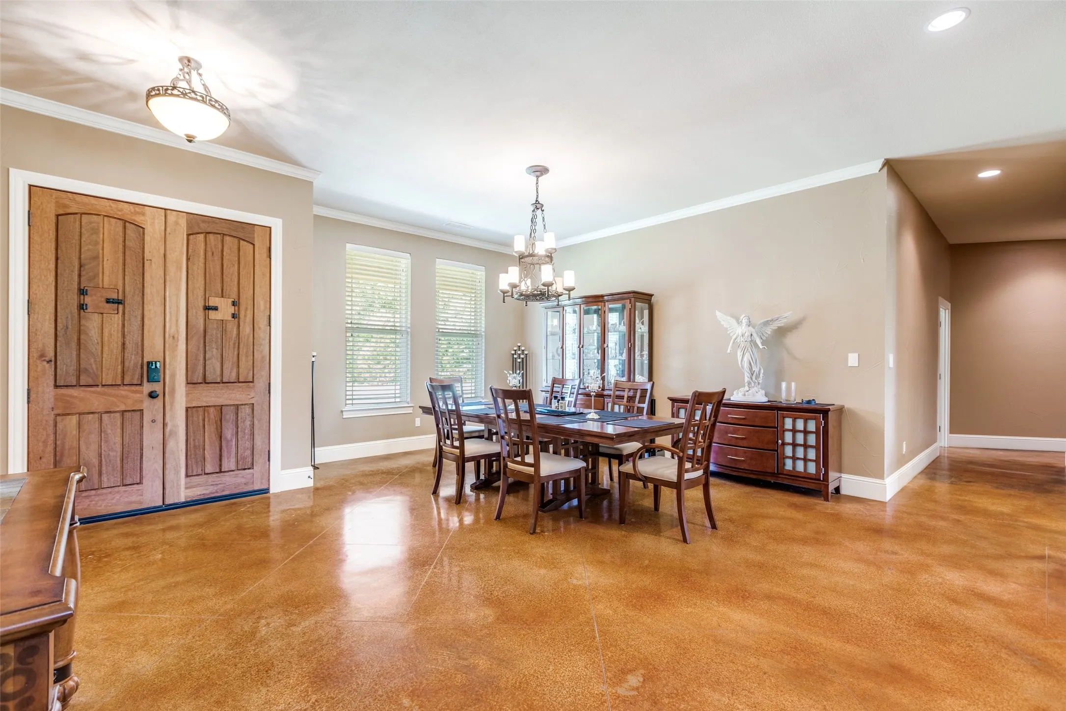 Dining room featuring finished concrete flooring, ornamental molding, and a chandelier
