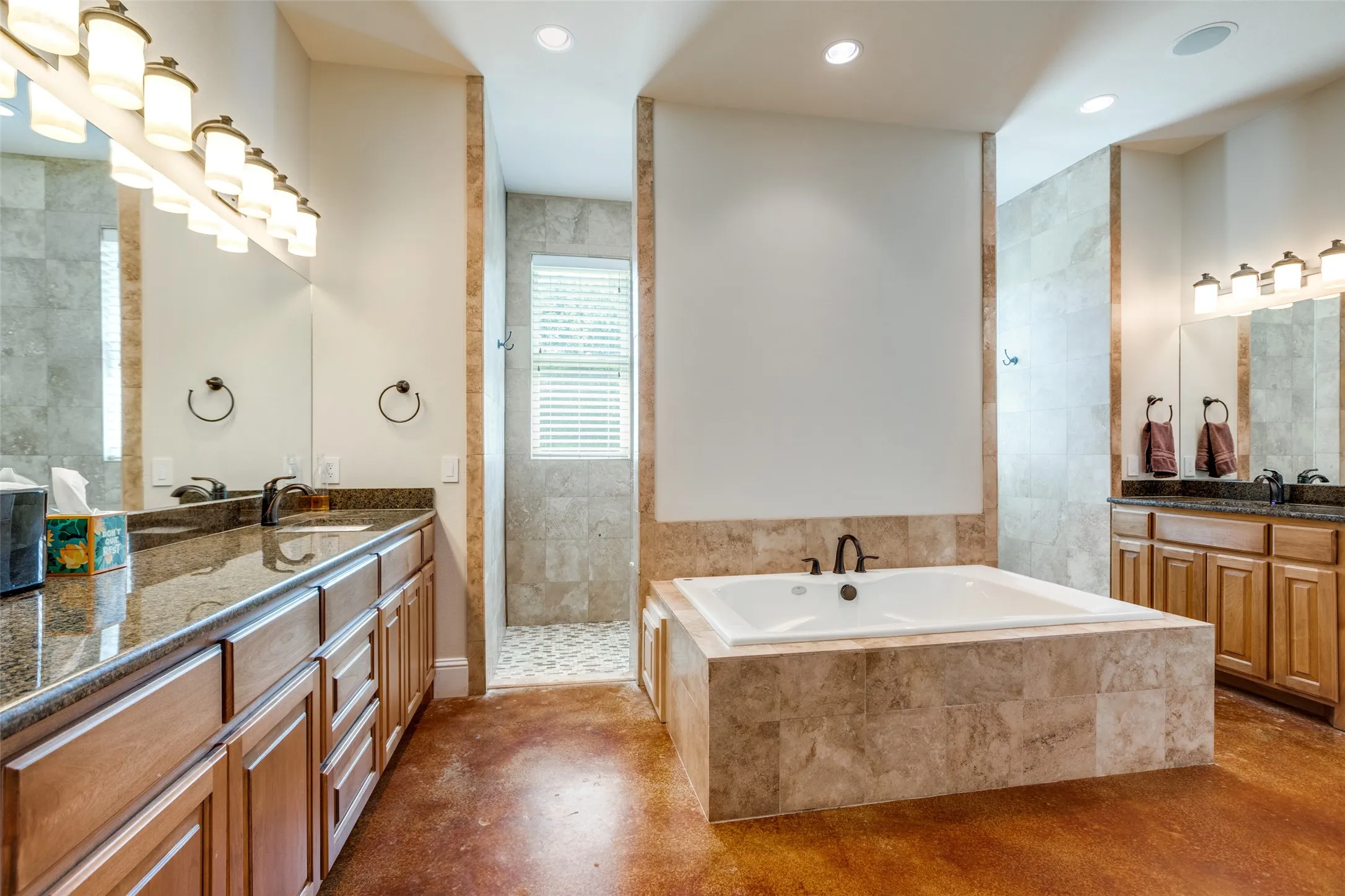 Bathroom featuring two vanities, a bath, recessed lighting, walk in shower, and finished concrete flooring