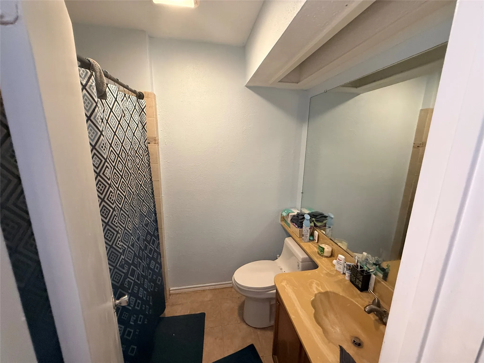 Full bath featuring vanity, curtained shower, and light tile patterned floors