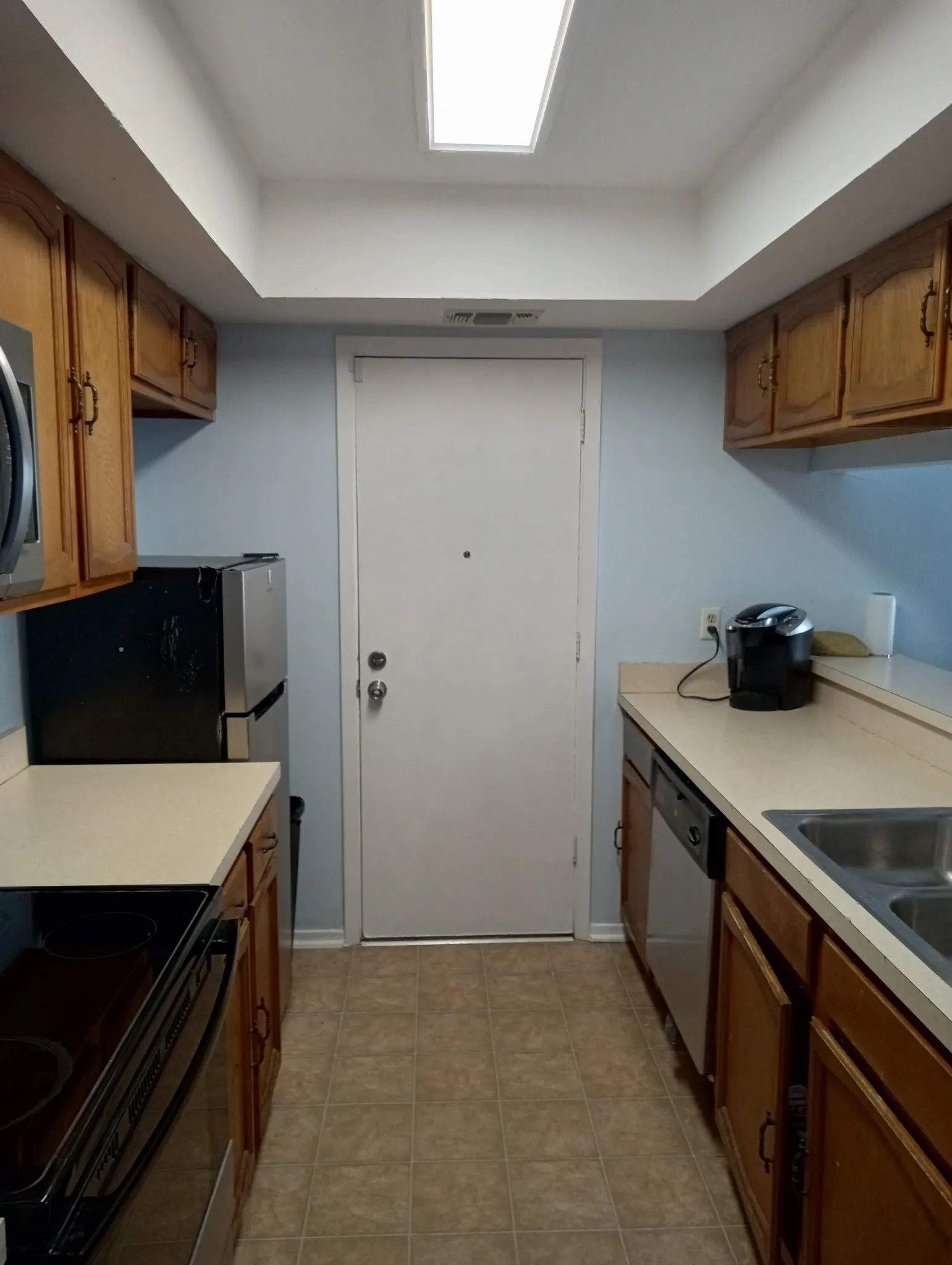 Kitchen with wood finish cabinets, stainless steel appliances, and light countertops