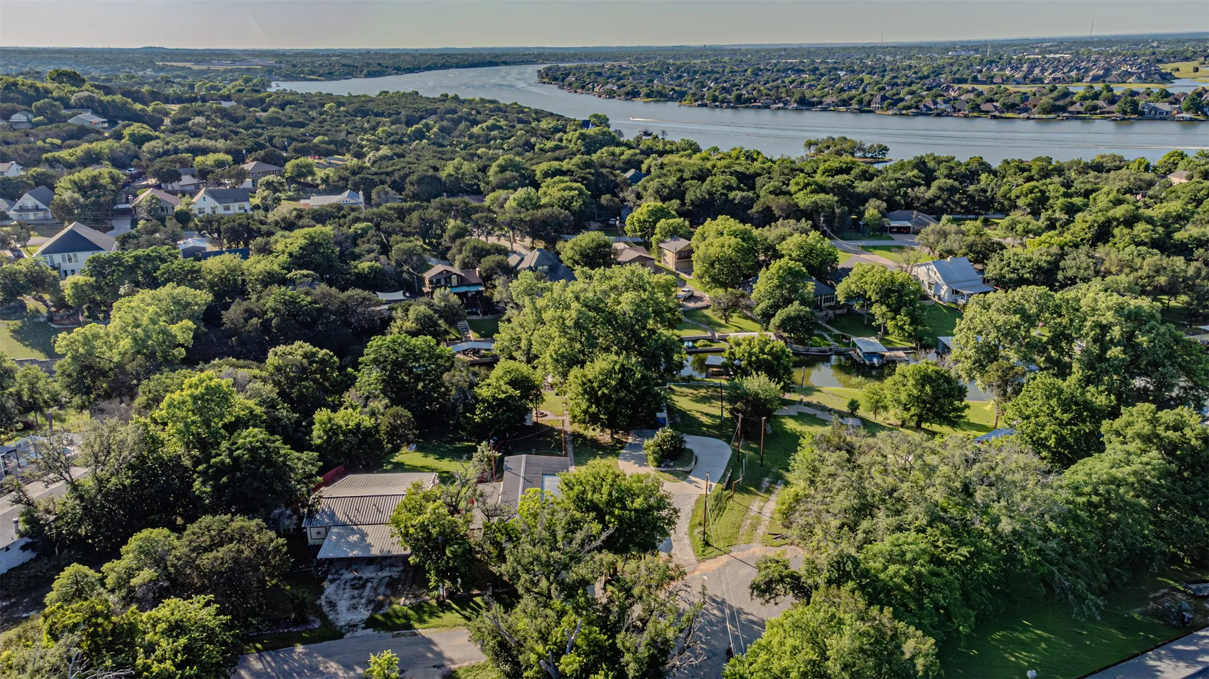 Aerial perspective showcasing a residential area featuring abundant mature trees and a prominent waterway