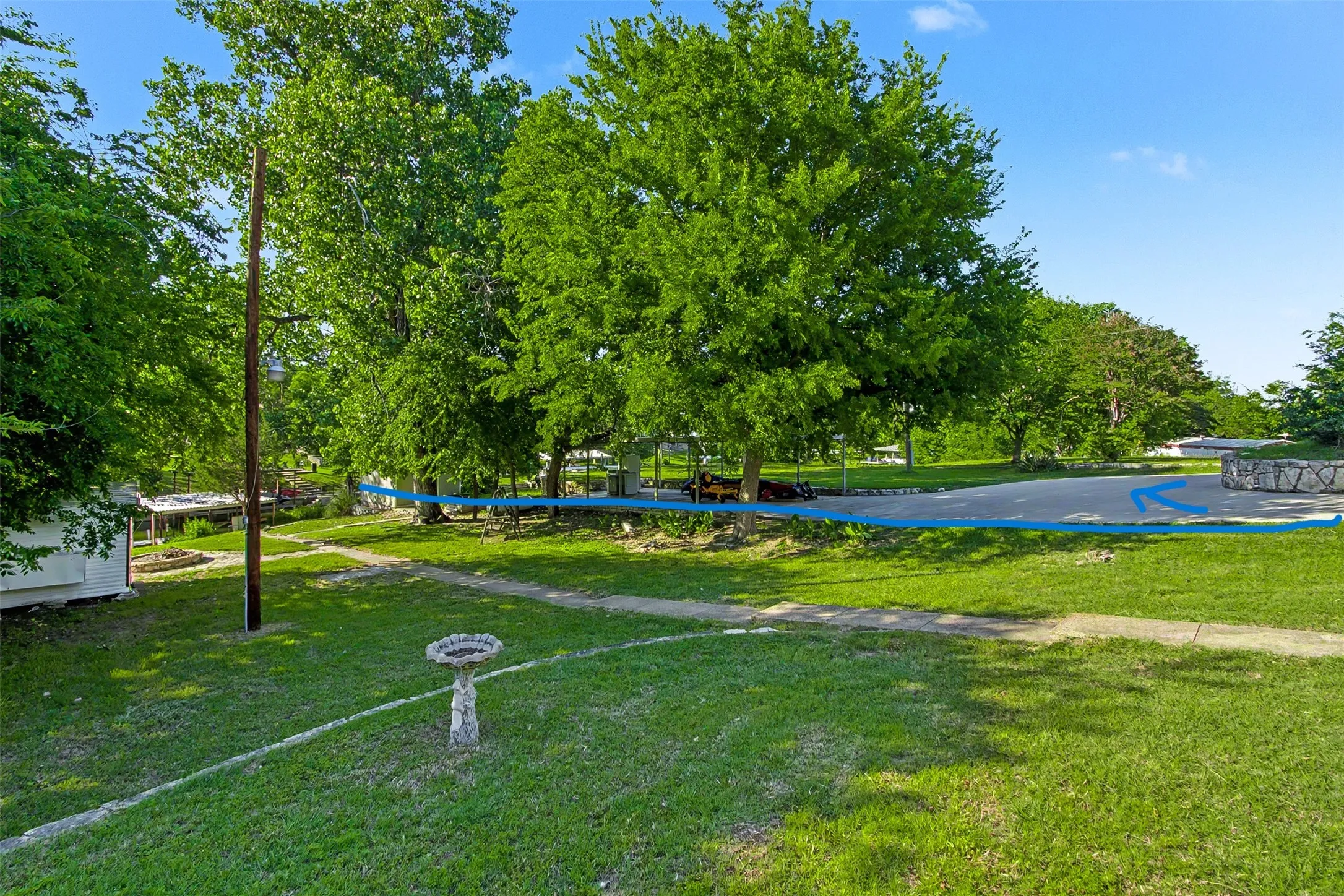 Expansive green lawn with mature trees and a paved driveway