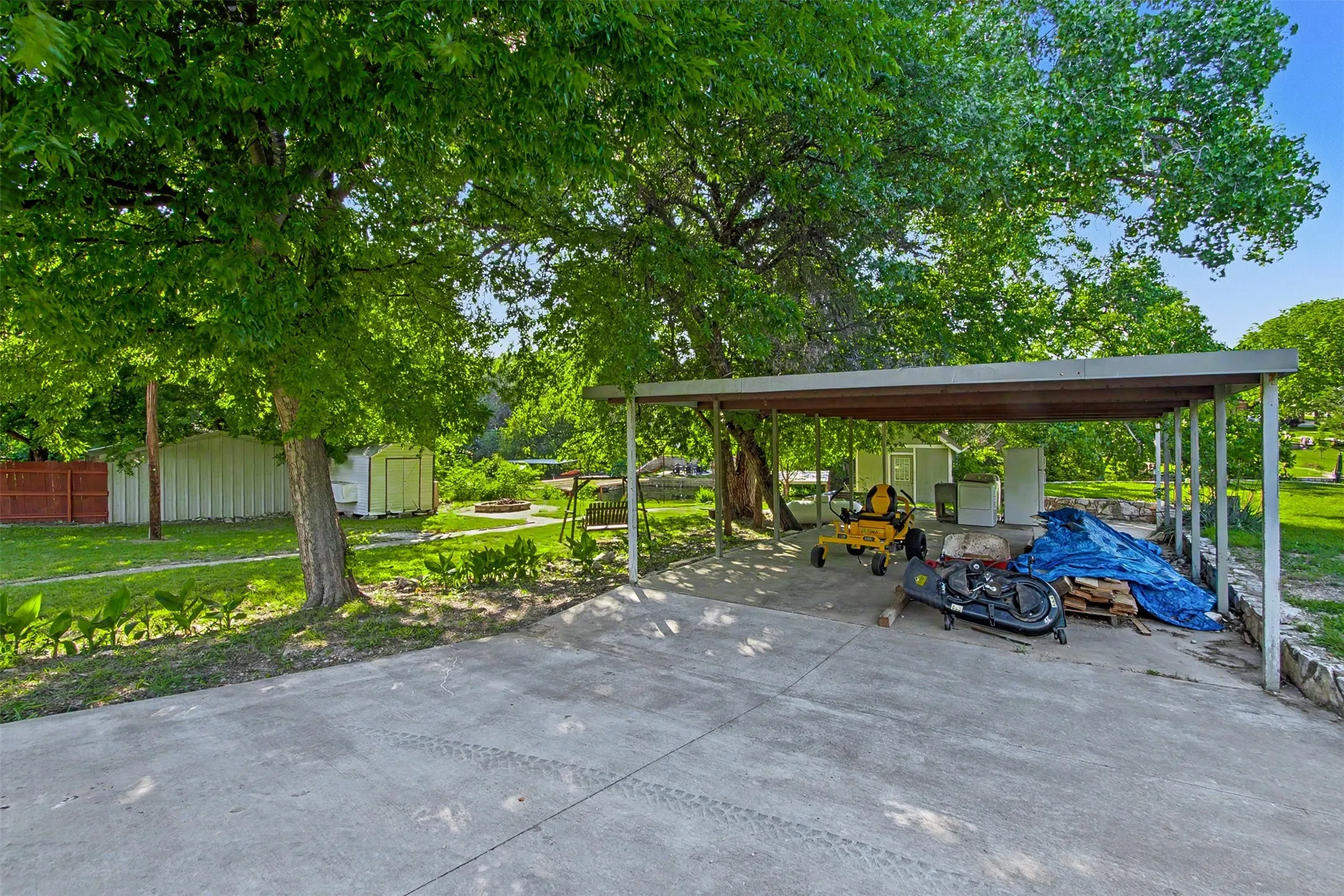 Expansive green lawn with mature trees and a paved driveway