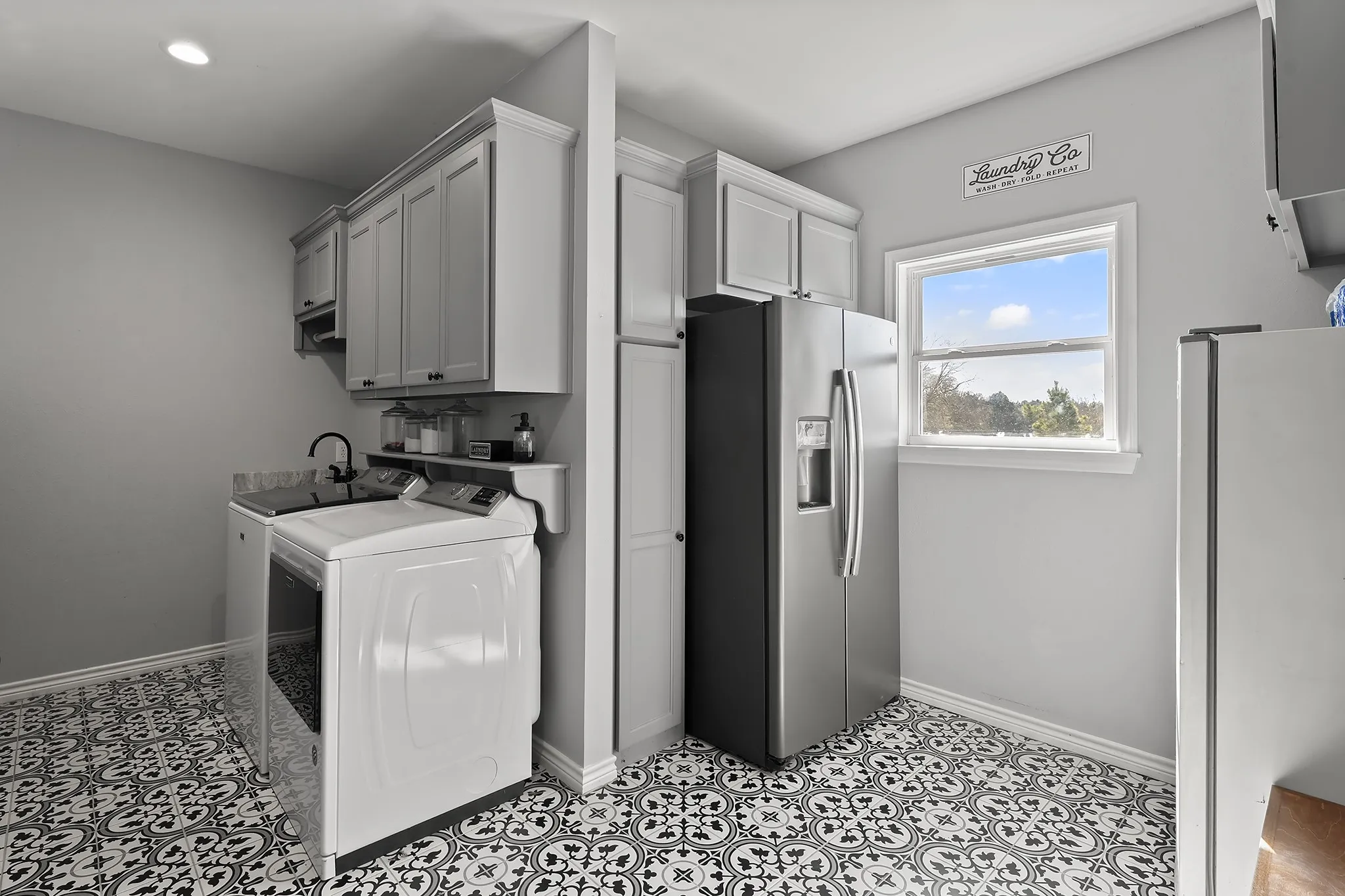 Laundry area with washer and clothes dryer, cabinet space, and light tile patterned floors