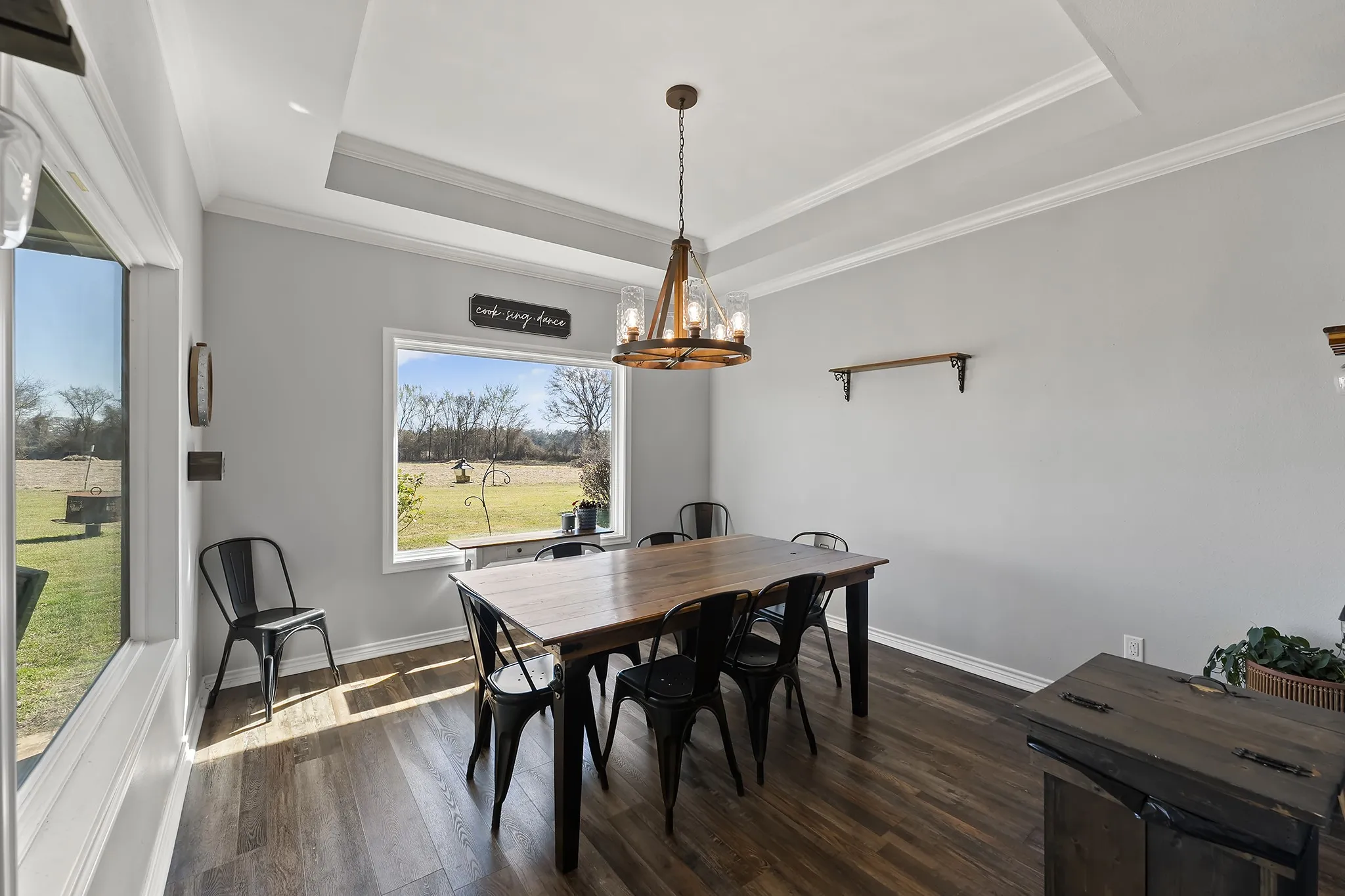 Dining area featuring dark wood-style flooring, a chandelier, crown molding, and a raised ceiling
