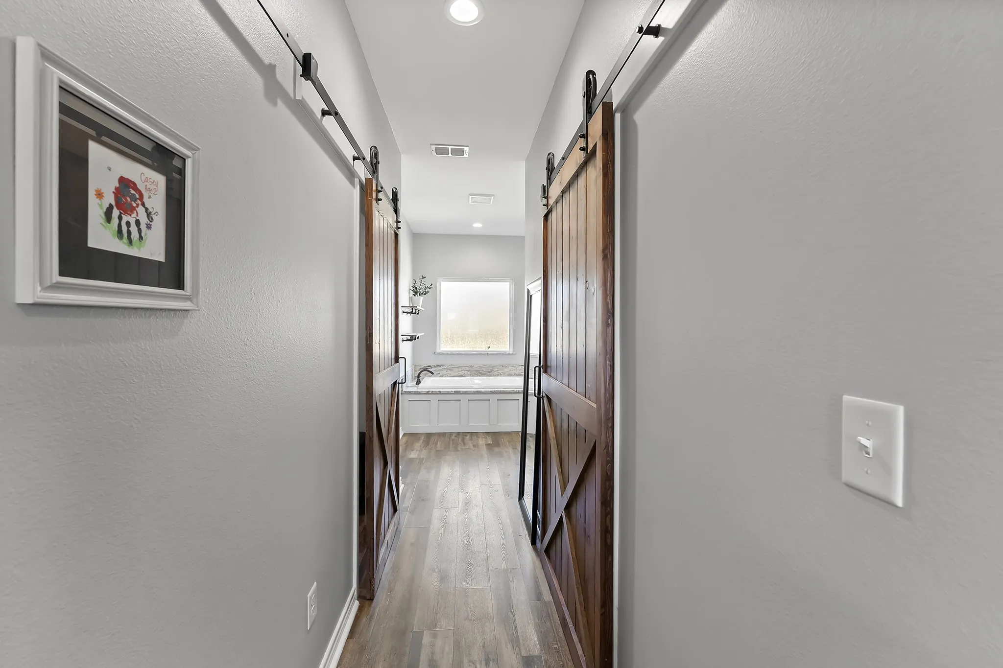 Hall with a textured wall, dark wood finished floors, and recessed lighting