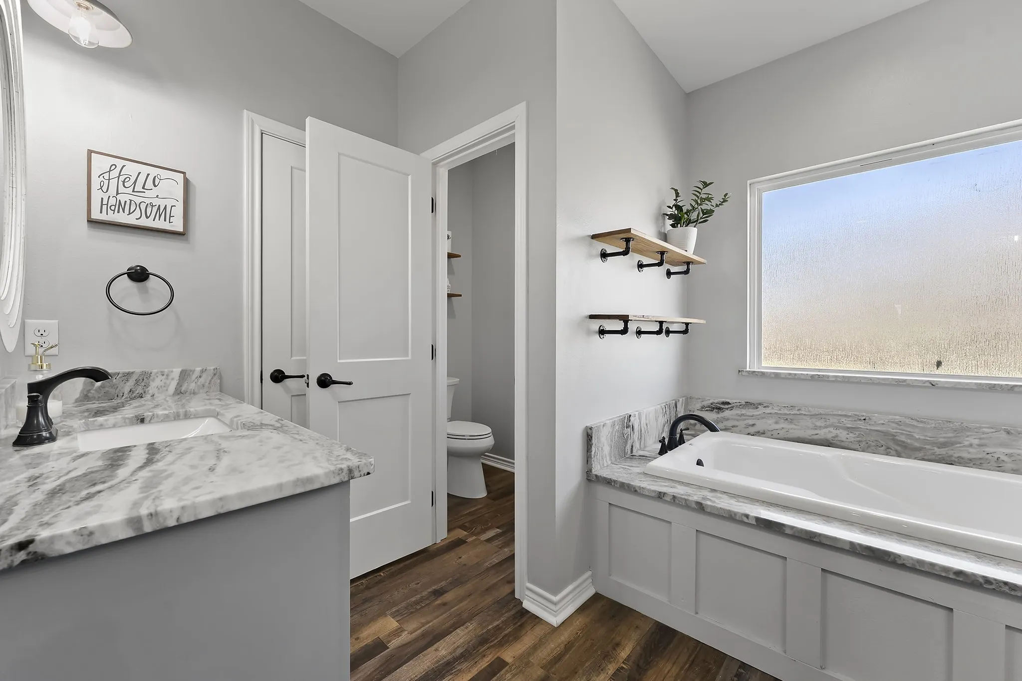 Full bath with vanity, a garden tub, and dark wood finished floors