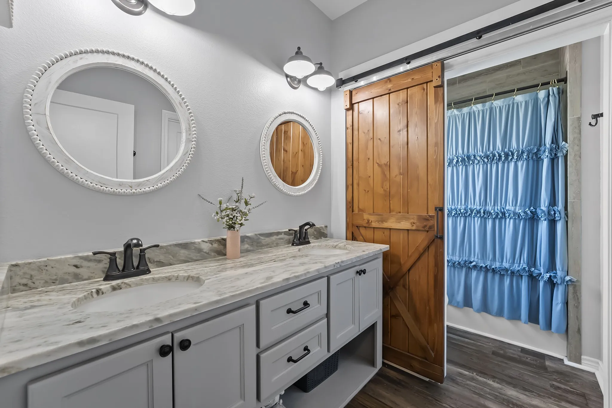 Full bath with double vanity and dark wood-style flooring
