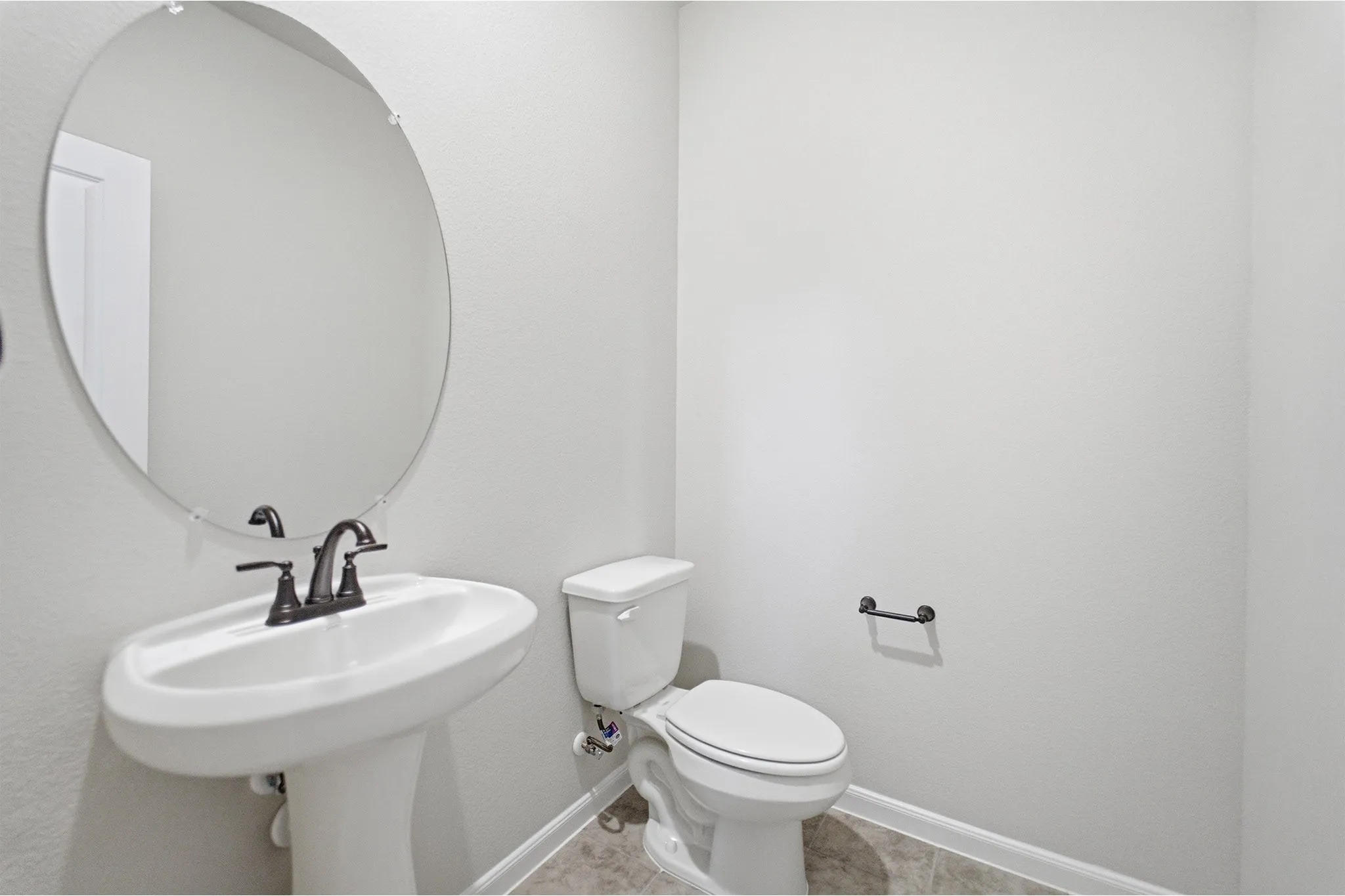 Pedestal sink with oil-rubbed bronze faucet and hardware, set against light gray walls