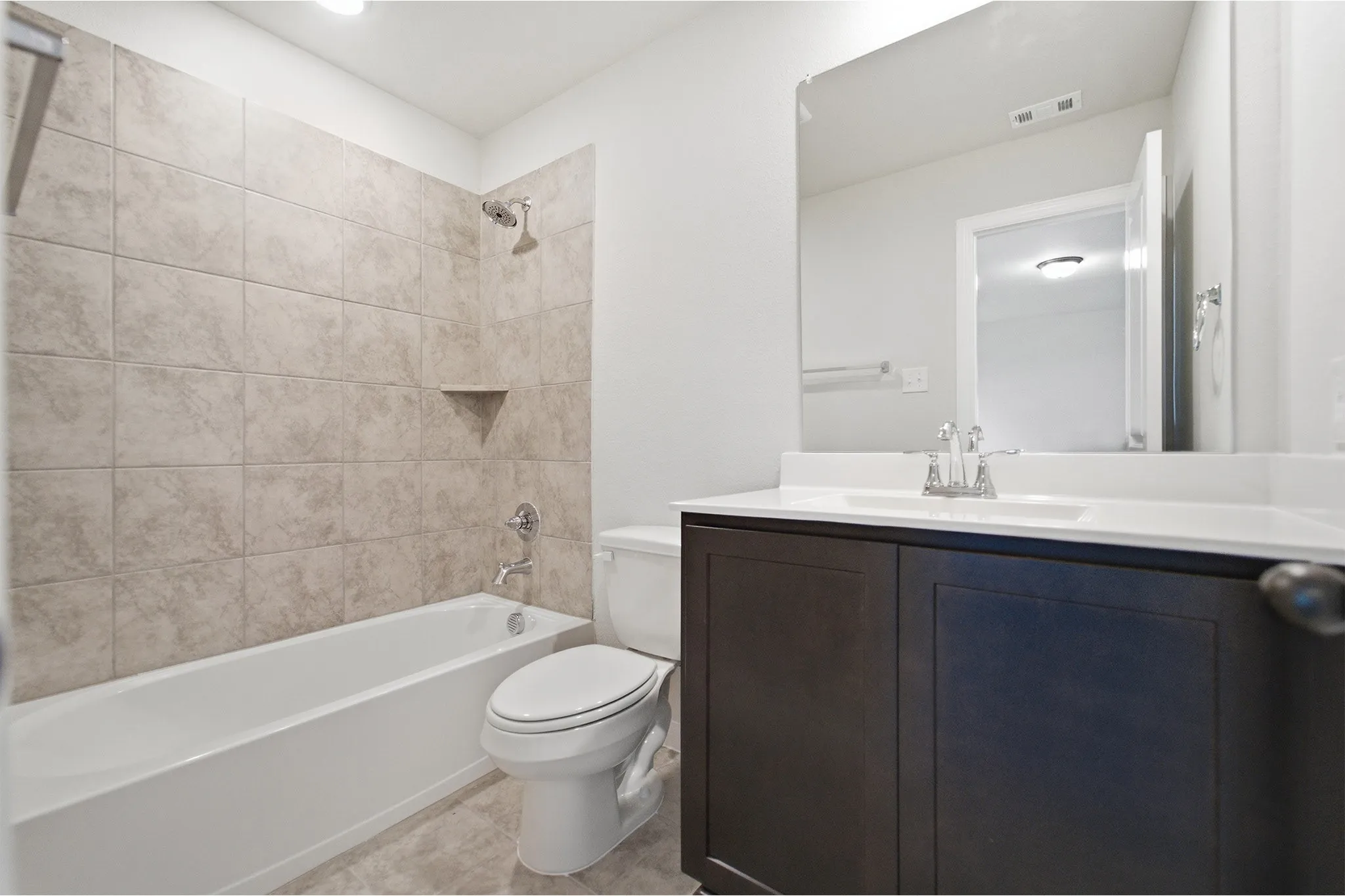 Bathroom featuring a dark wood-finish vanity with an integrated white sink, a full-width mirror, and a toilet