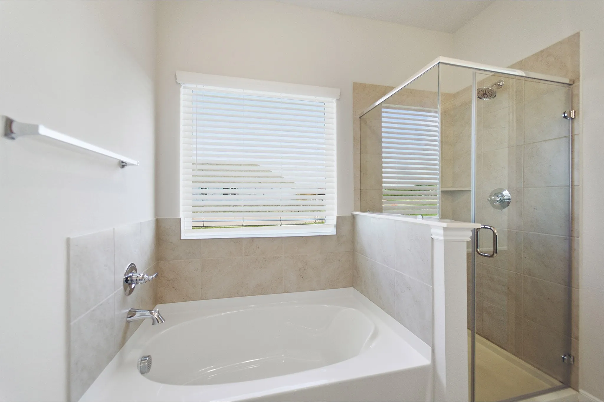 White soaking tub with chrome fixtures and light-toned tile surround