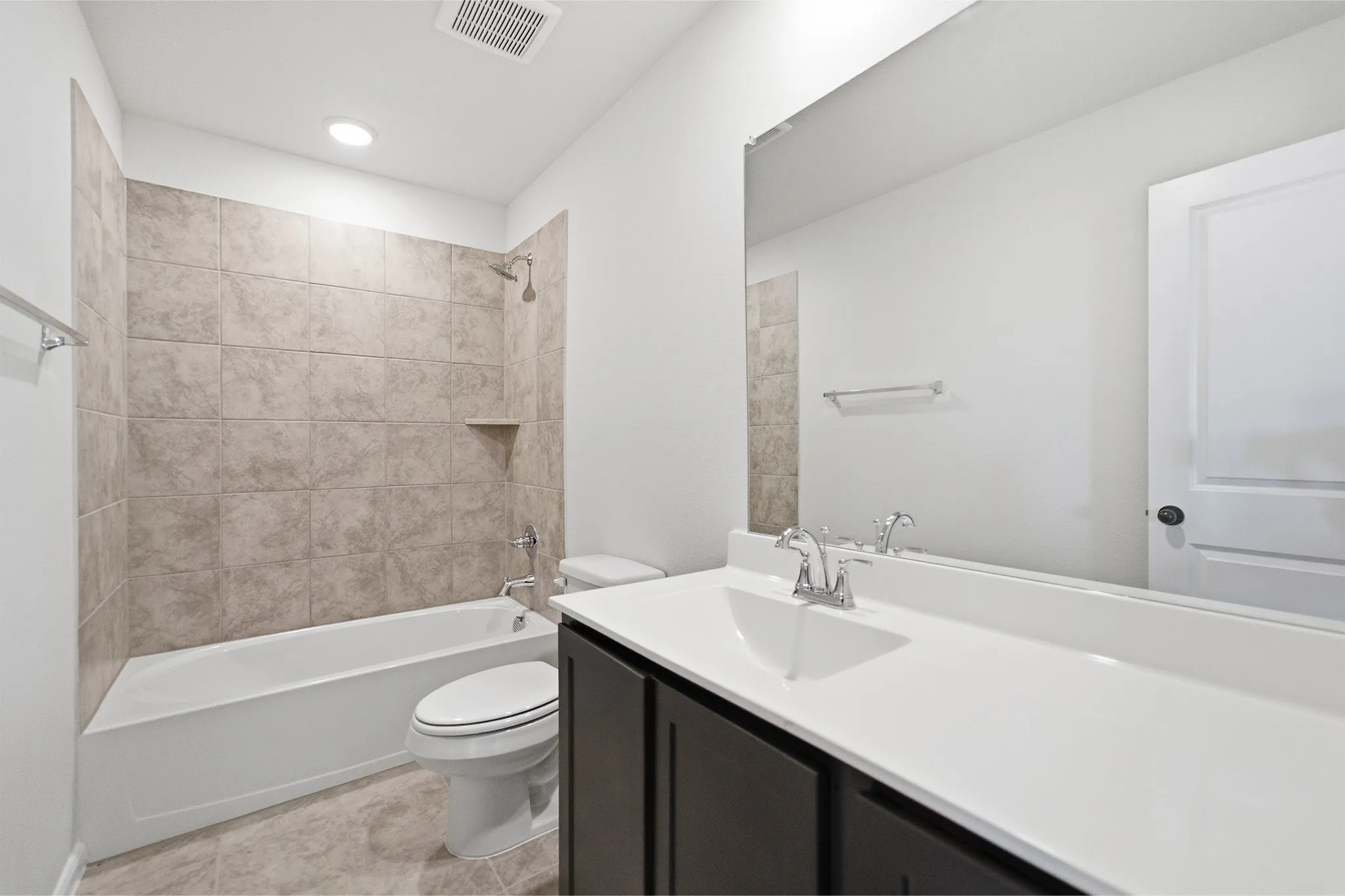 Full bathroom featuring a white tub with light-colored tile surround, a built-in shower niche, and a chrome shower head