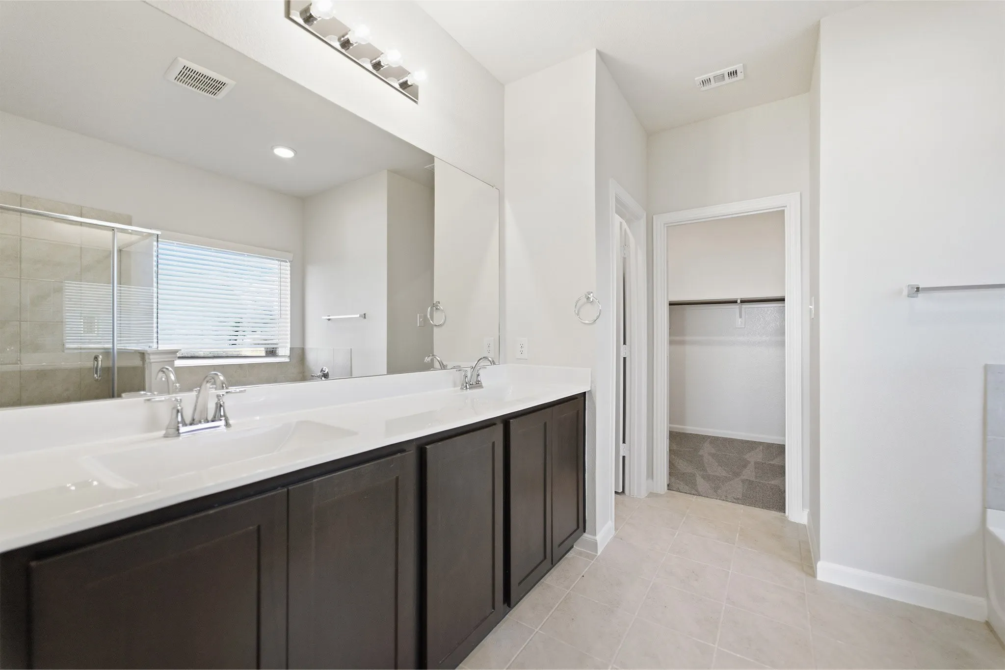 Dual vanity featuring integrated sinks, dark wood-finish cabinetry, and chrome fixtures