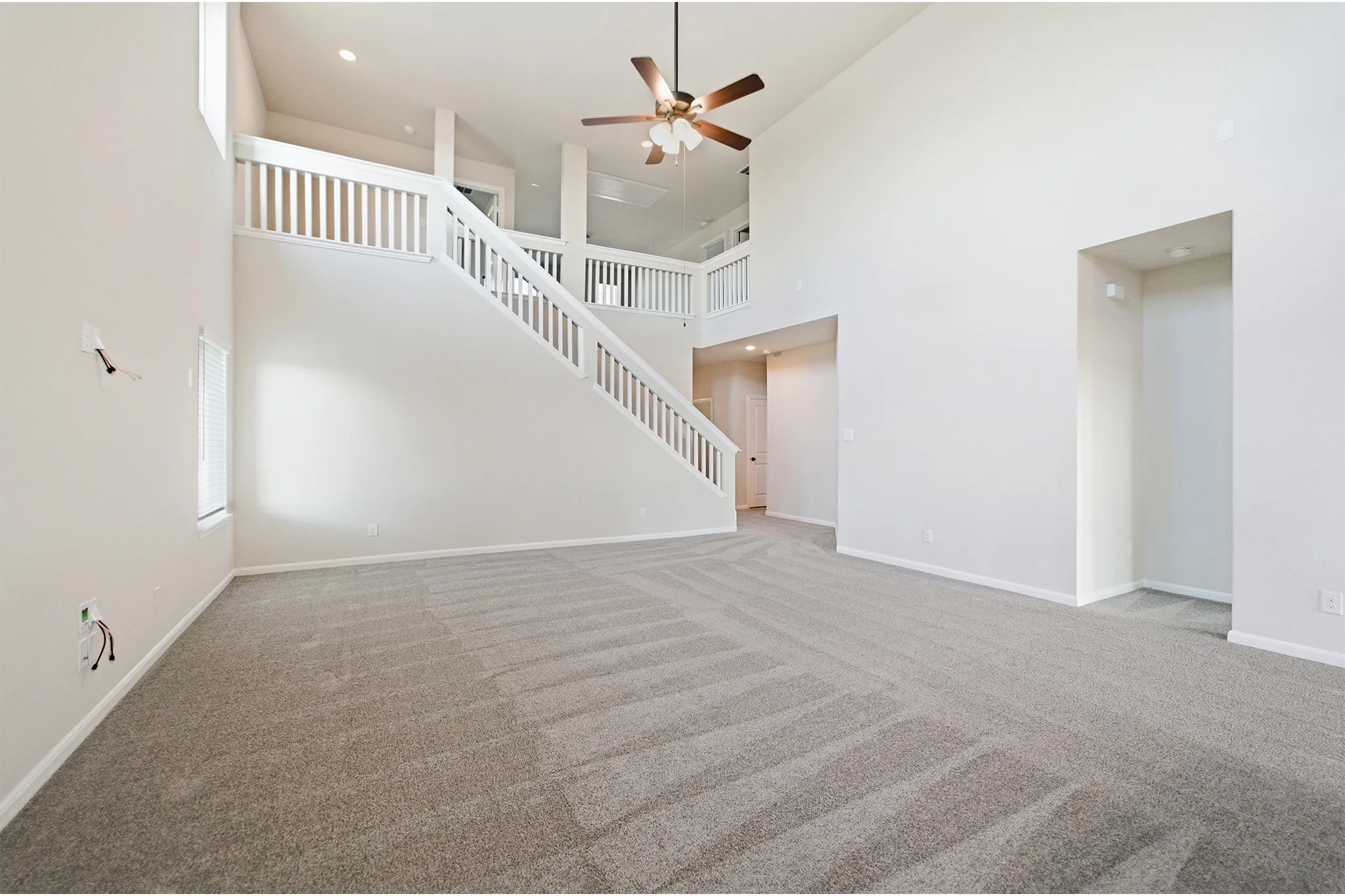 Two-story living area featuring high ceilings, neutral-toned walls, and grey patterned carpeting