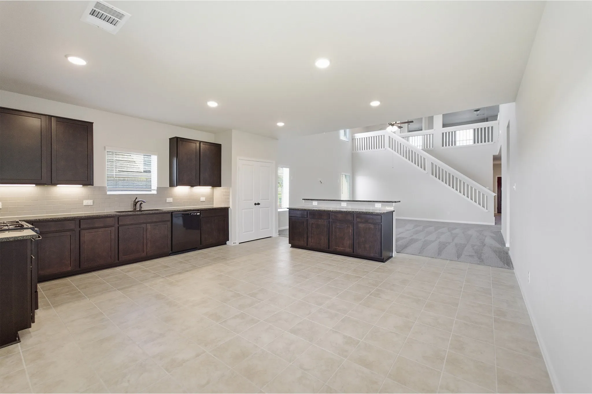 Spacious kitchen with tile flooring, dark wood cabinetry, and recessed lighting
