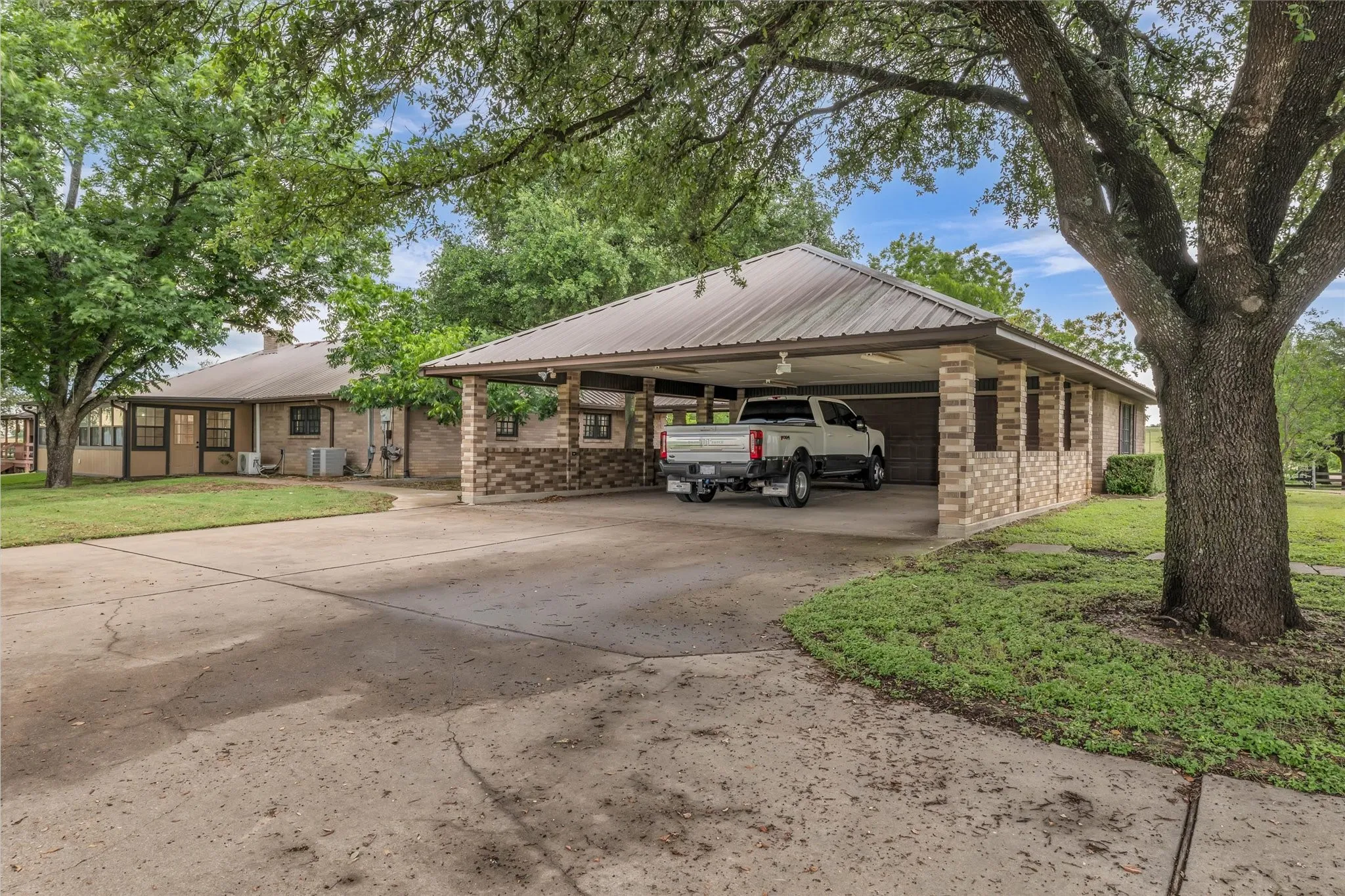 View of front of home featuring brick siding, driveway, a front lawn, and an attached carport