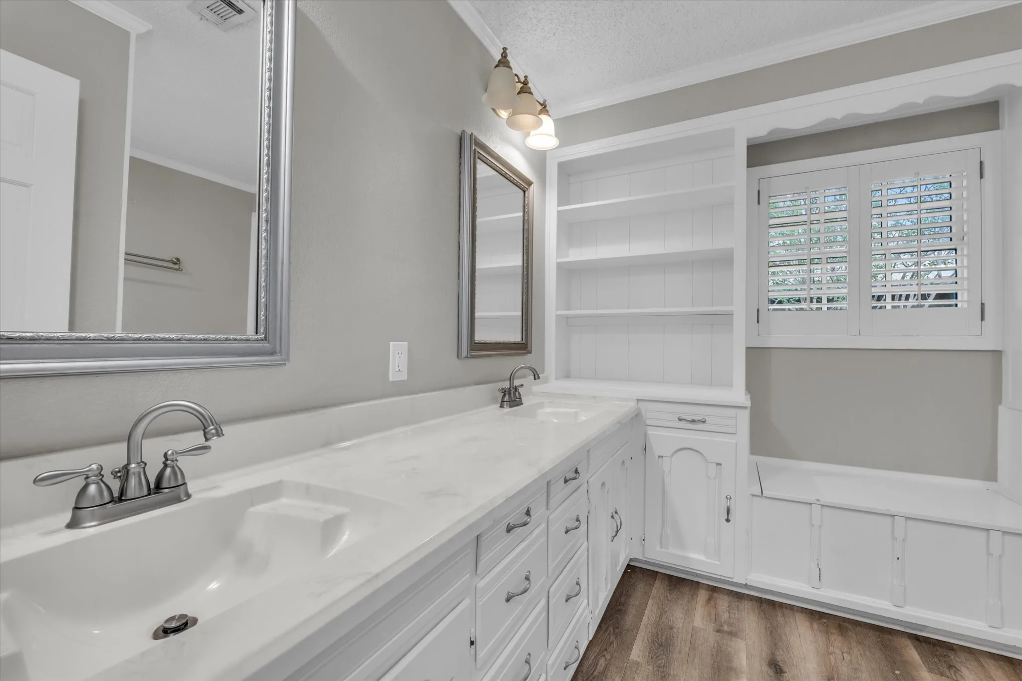 Full bath featuring crown molding, double vanity, wood finished floors, and a textured ceiling