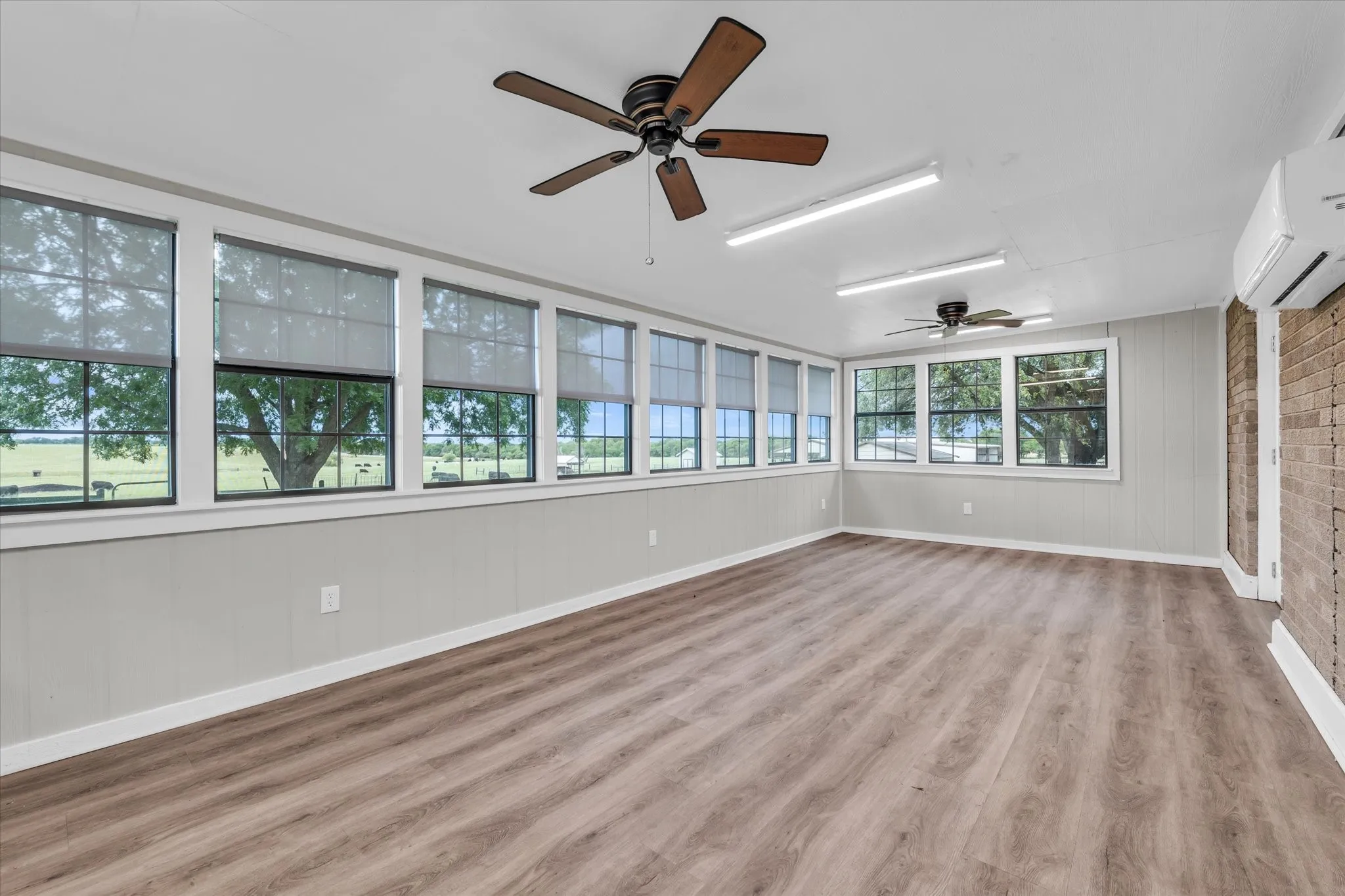 Unfurnished sunroom featuring a wall unit AC and wood finished floors