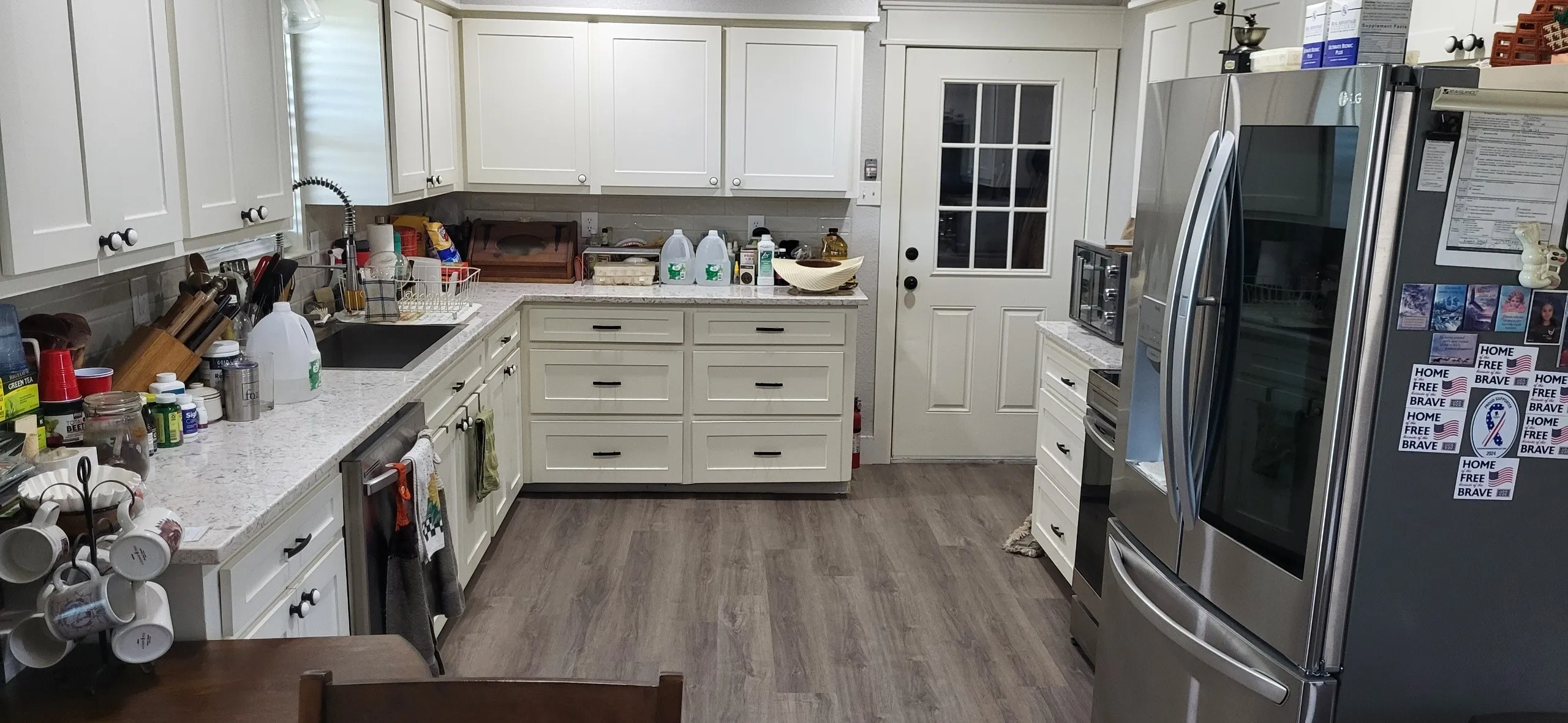 Kitchen with light stone countertops, light hardwood / wood-style flooring, stainless steel appliances, and white cabinets